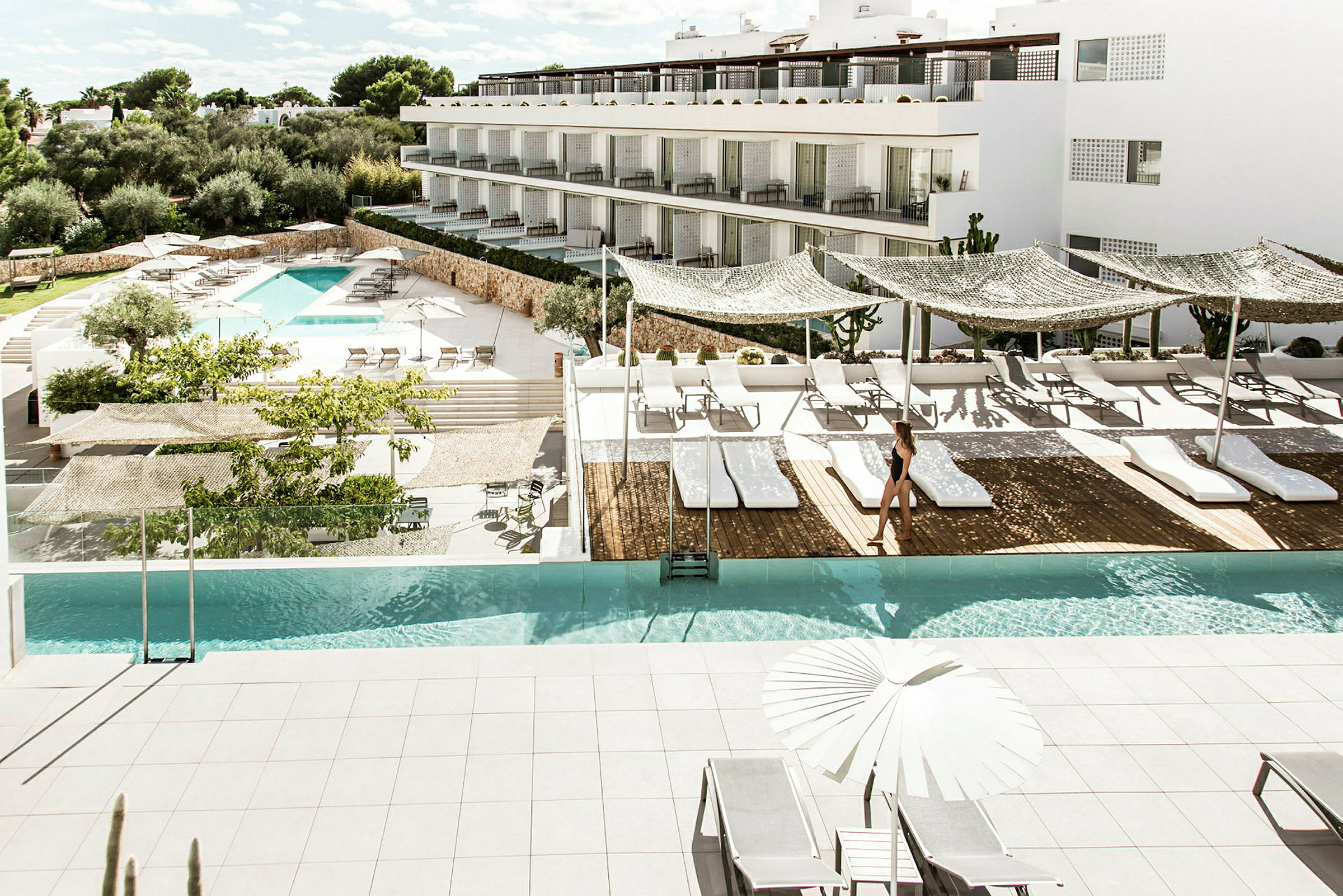 Et moderne hotellbasseng med solsenger og parasoller på en solrik terrasse. (AI-generert tekst)