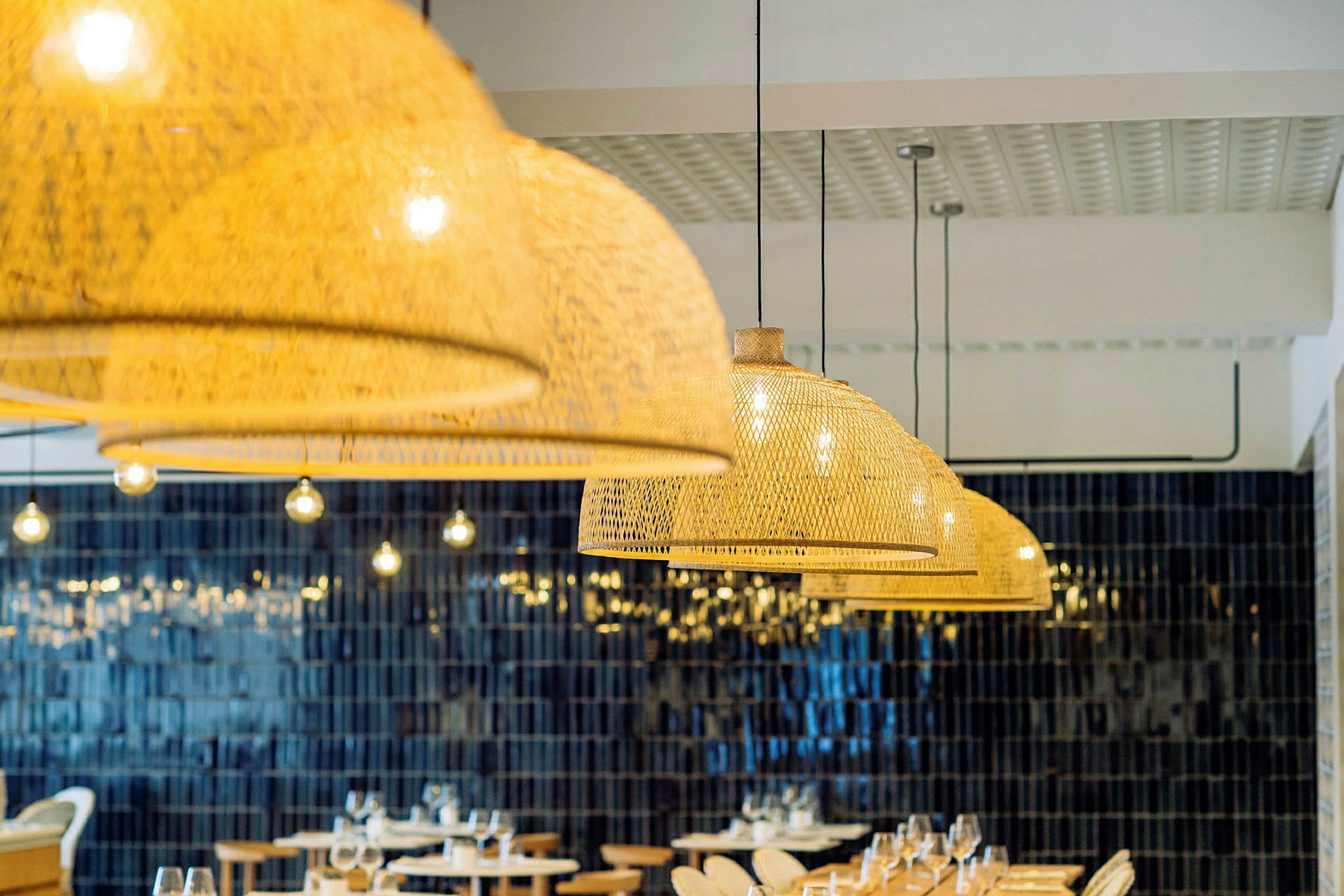 Restaurantinteriør med hengende flettede lampeskjermer og bord med dekket bord. (AI-generert tekst)