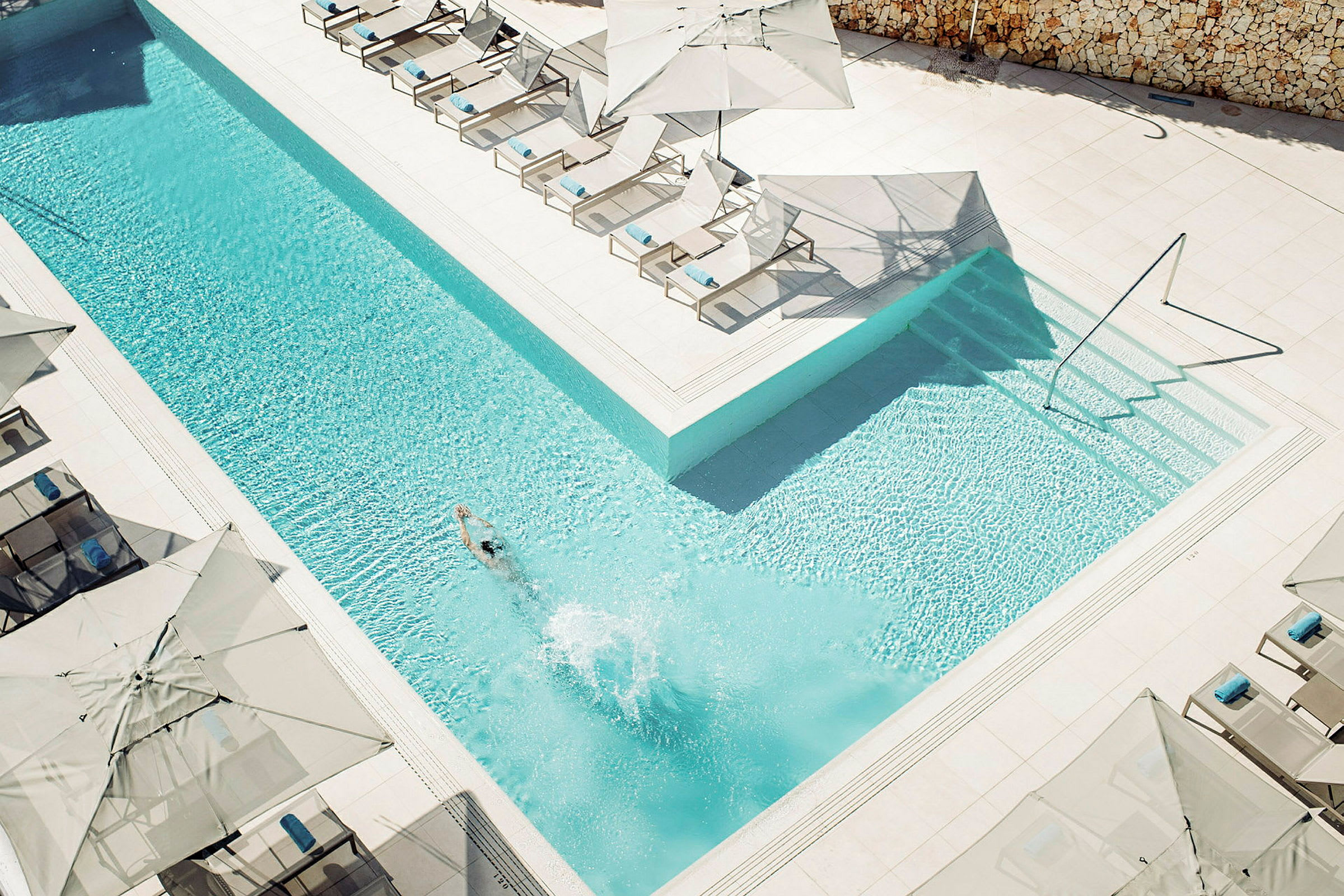 Utendørsbasseng med solsenger og parasoller. (AI-generert tekst)