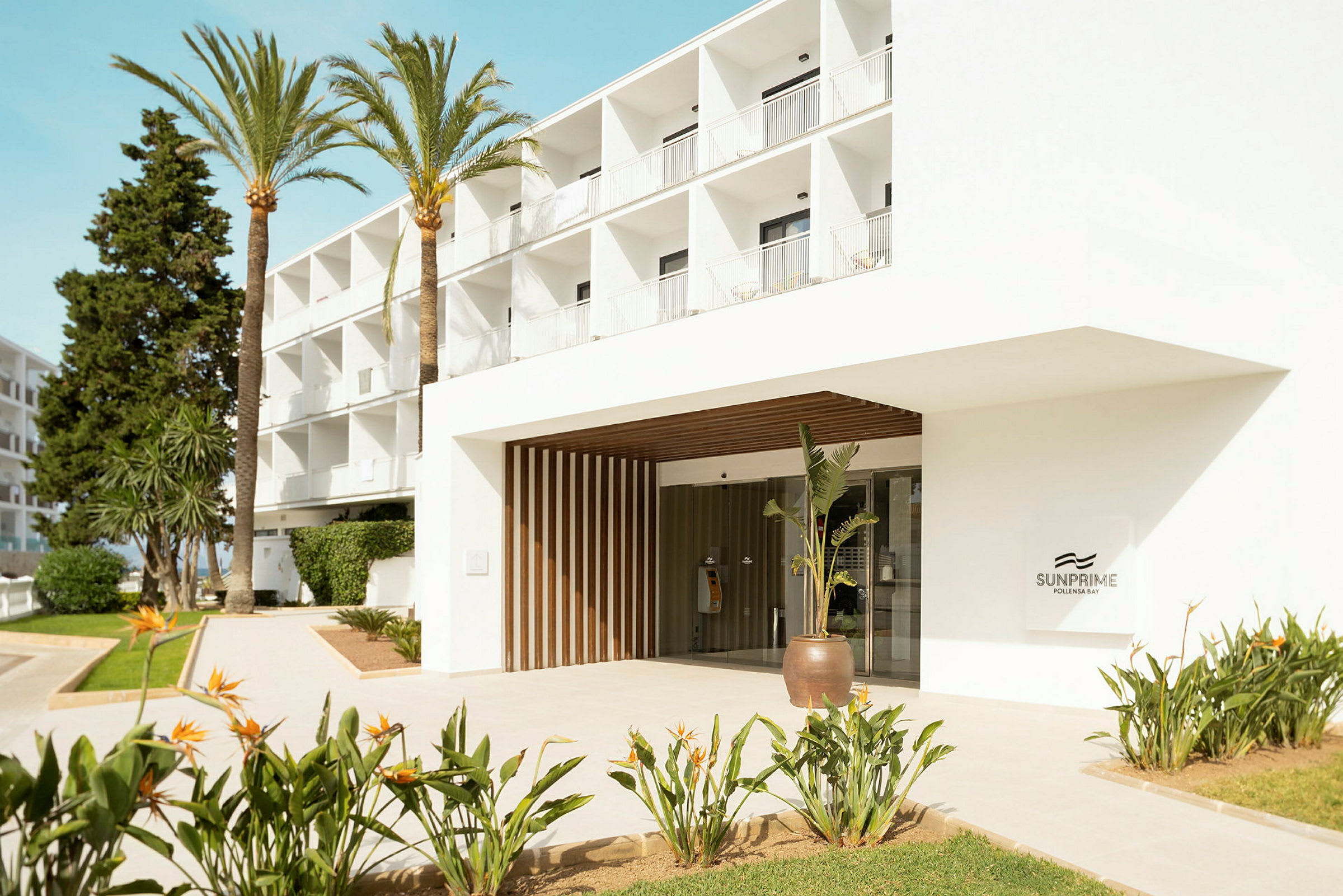 Inngang til hotell Sunprime med omkringliggende planter og palmer. (AI-generert tekst)