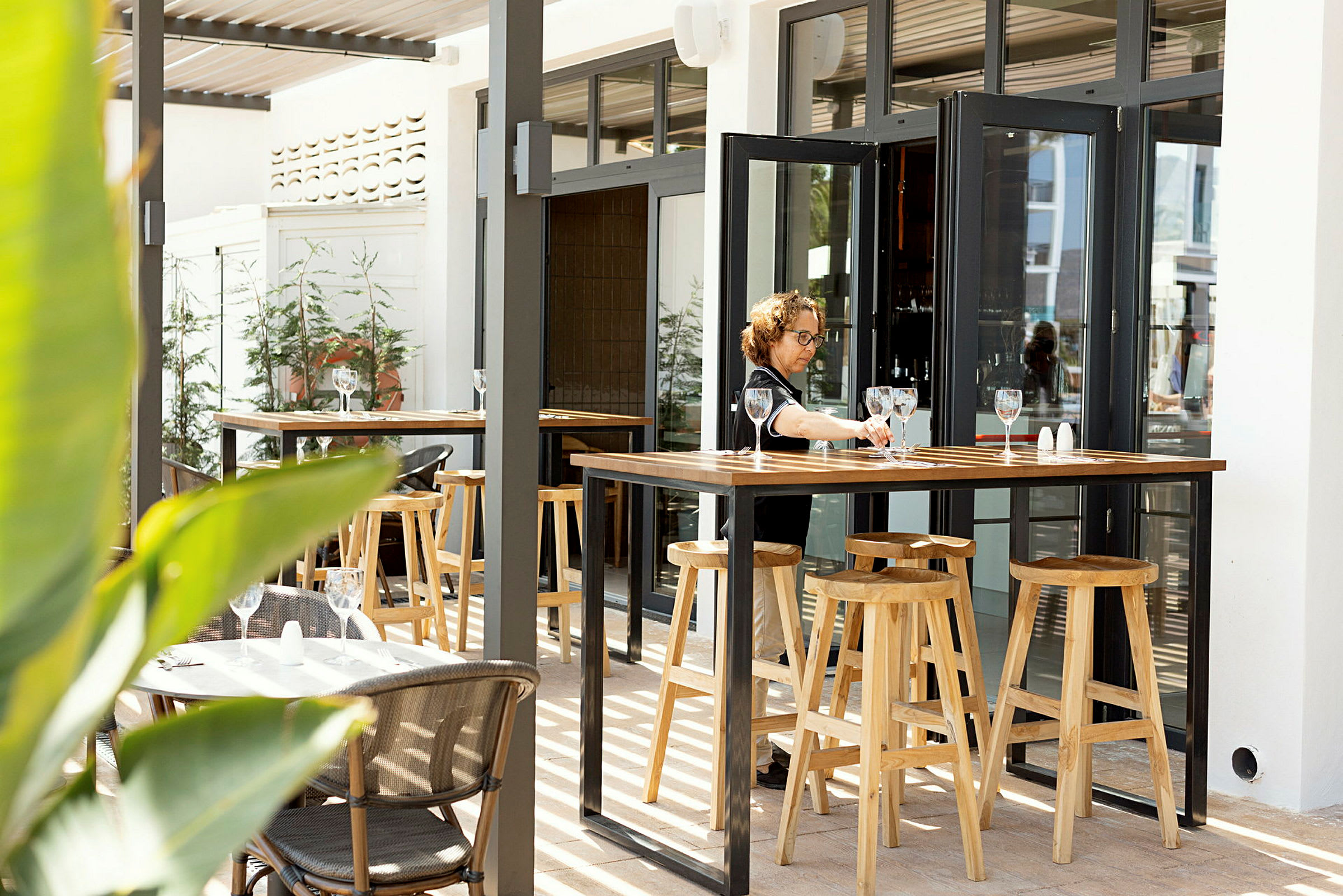 En utendørs restaurant med bord og høye trepaller. (AI-generert tekst)
