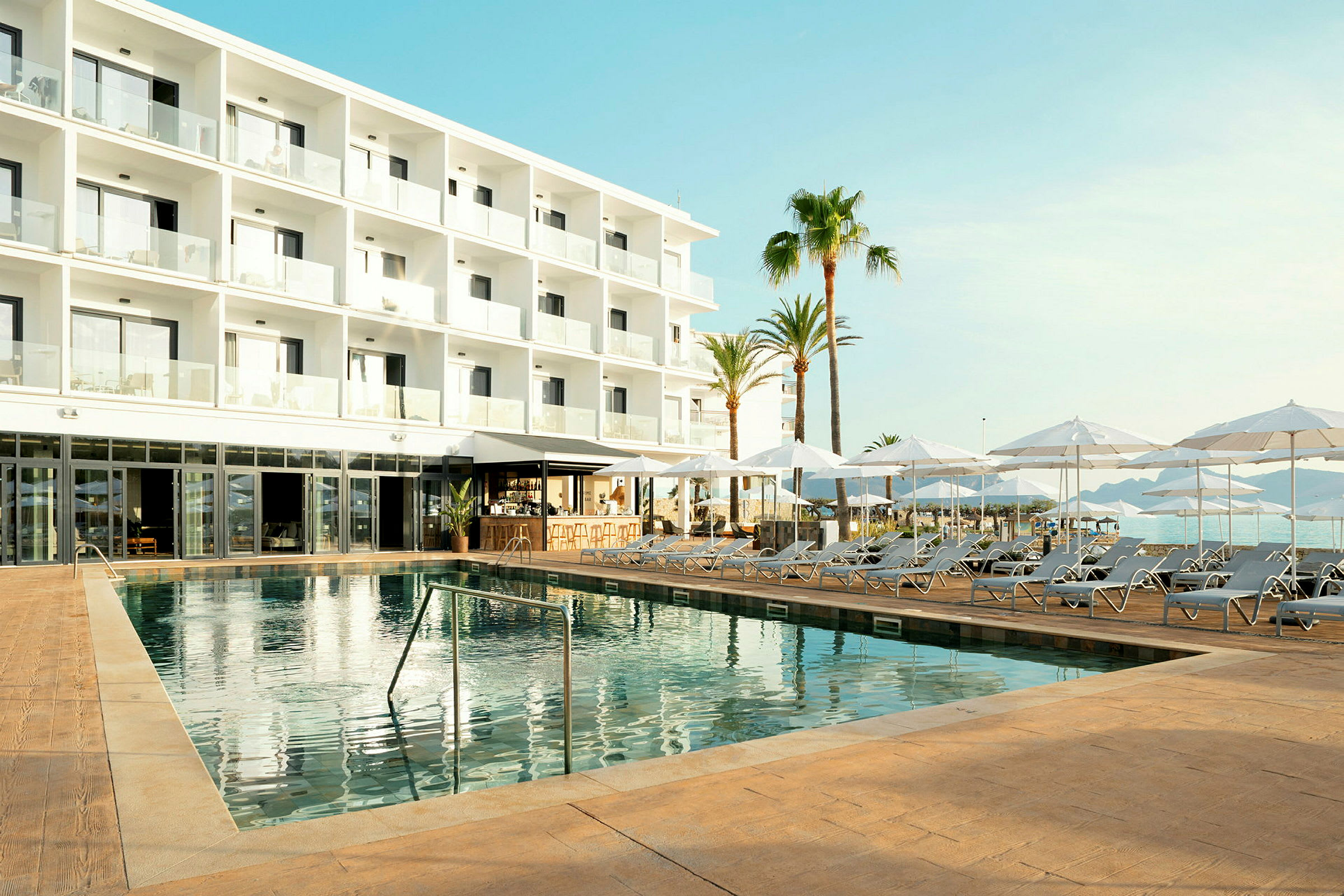 Moderne hotellbygning med områder for solsenger og parasoller samt et svømmebasseng. (AI-generert tekst)