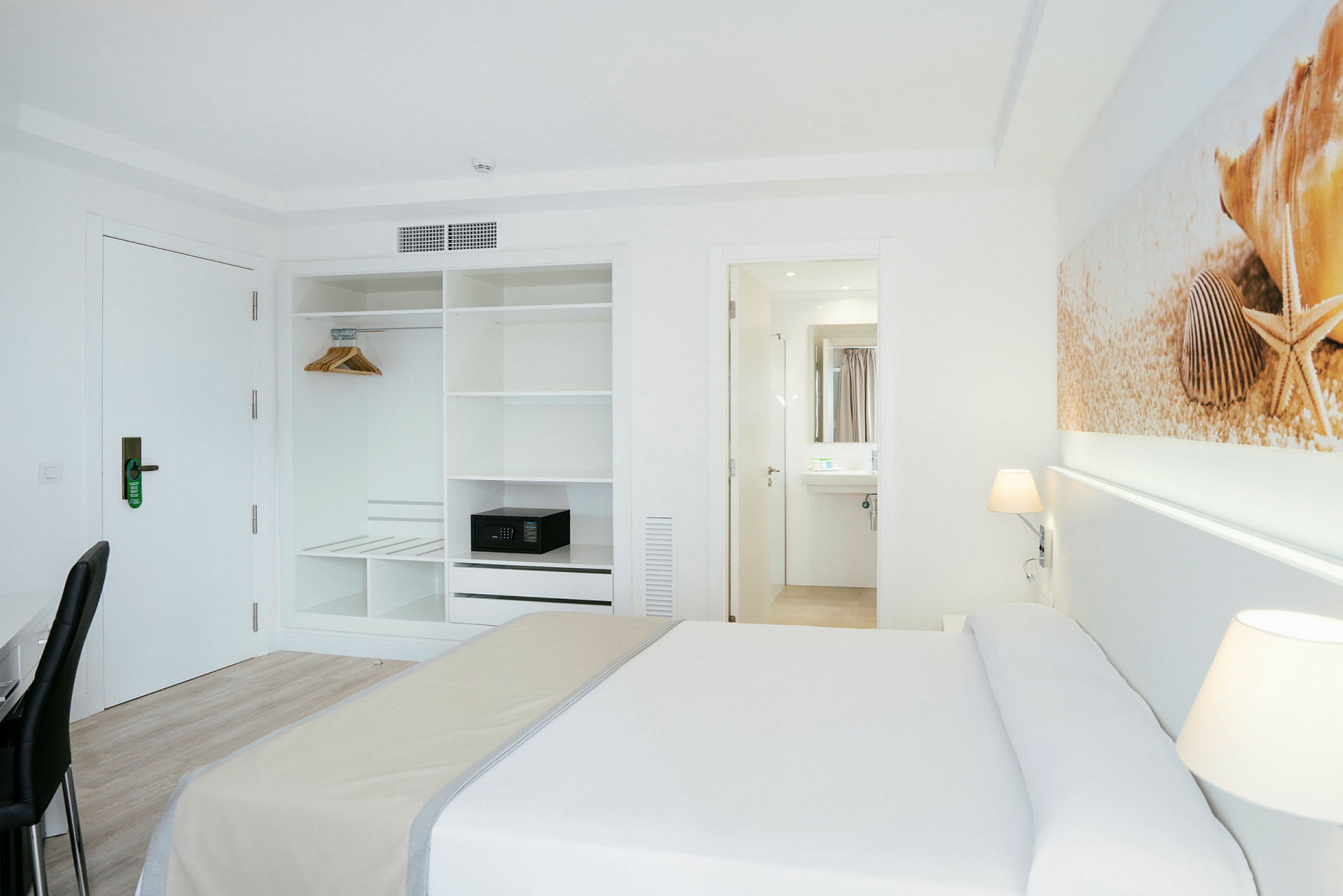 Hotellrom med seng, garderobe og inngang til et bad. (AI-generert tekst)
