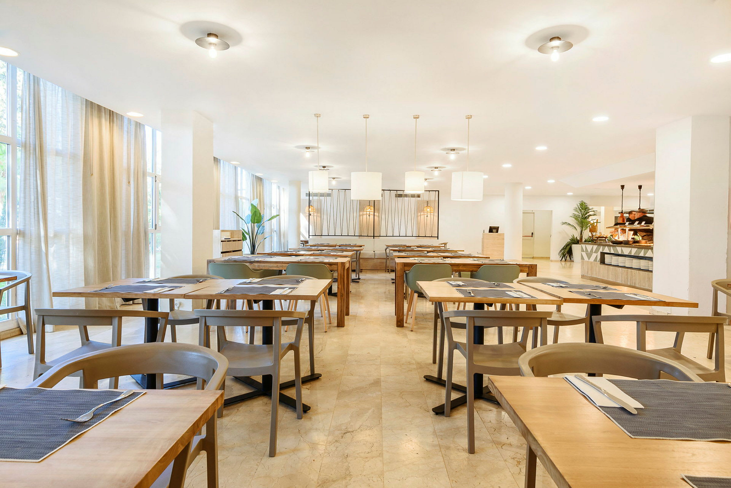En lyst innredet restaurant med oppstilte bord og stoler. (AI-generert tekst)