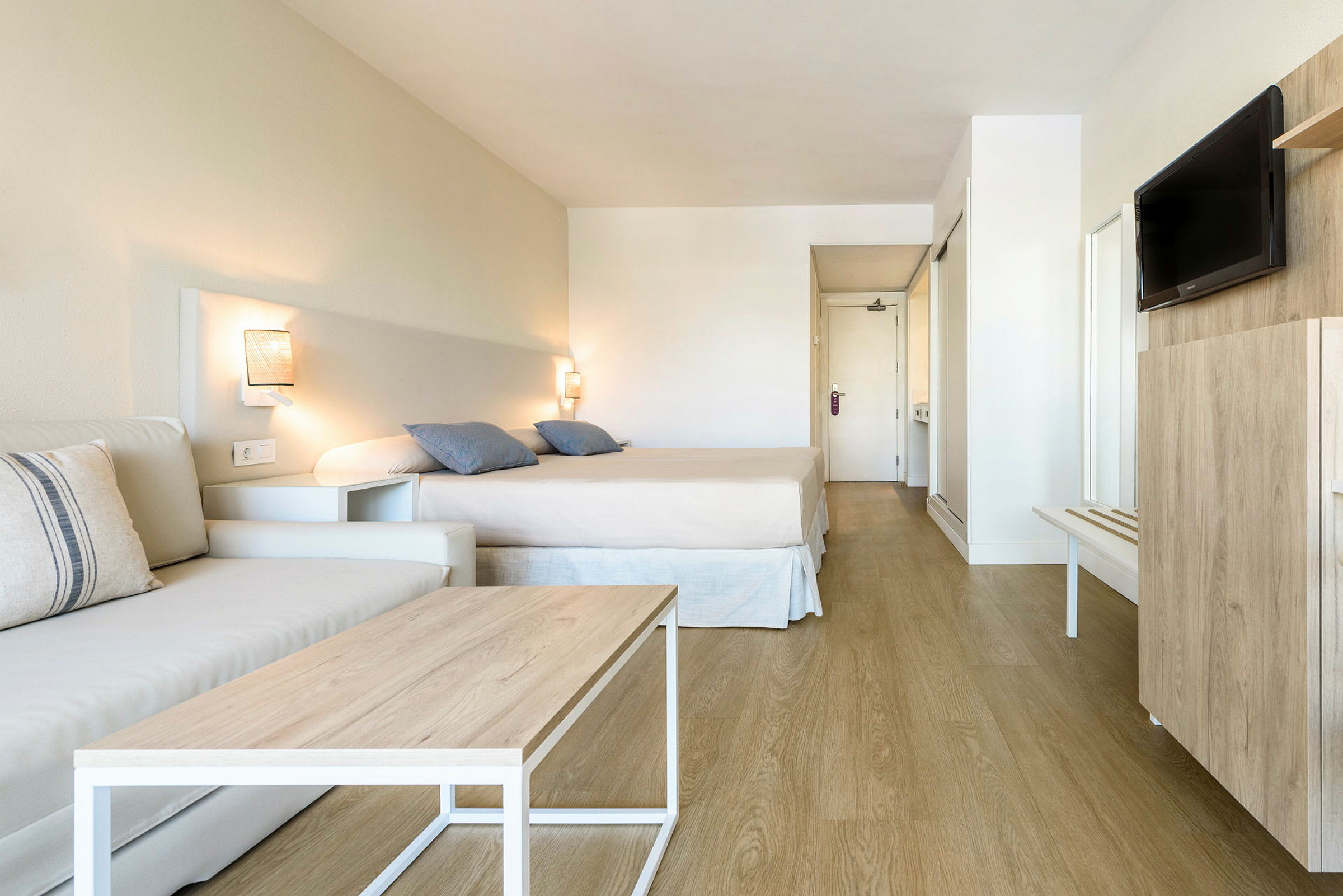 Et hotellrom med seng, sofa og TV. (AI-generert tekst)