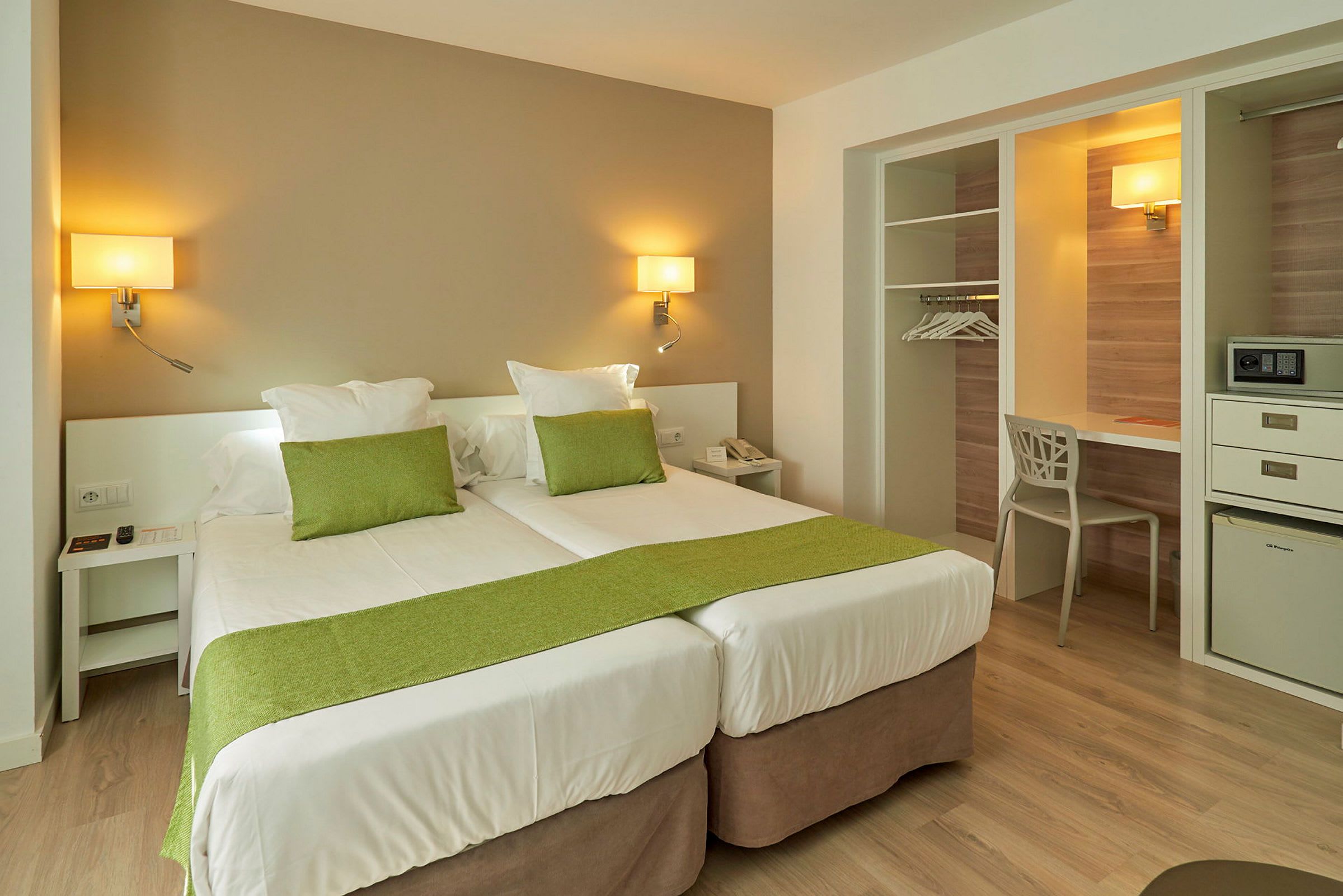 Hotellrom med to enkeltsenger og grønn dekorasjon. (AI-generert tekst)