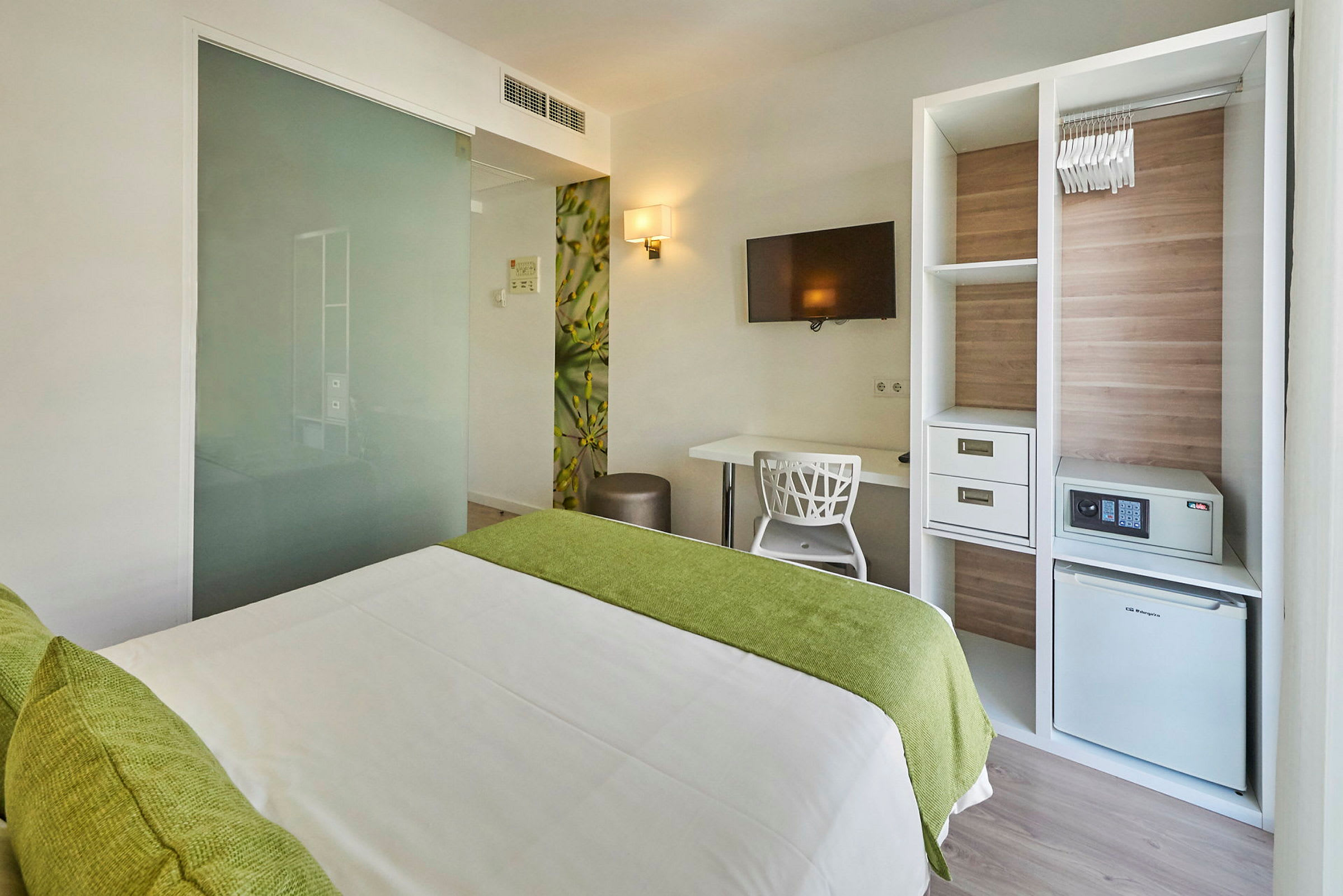 Moderne hotellrom med seng, skrivebord, TV og garderobe. (AI-generert tekst)