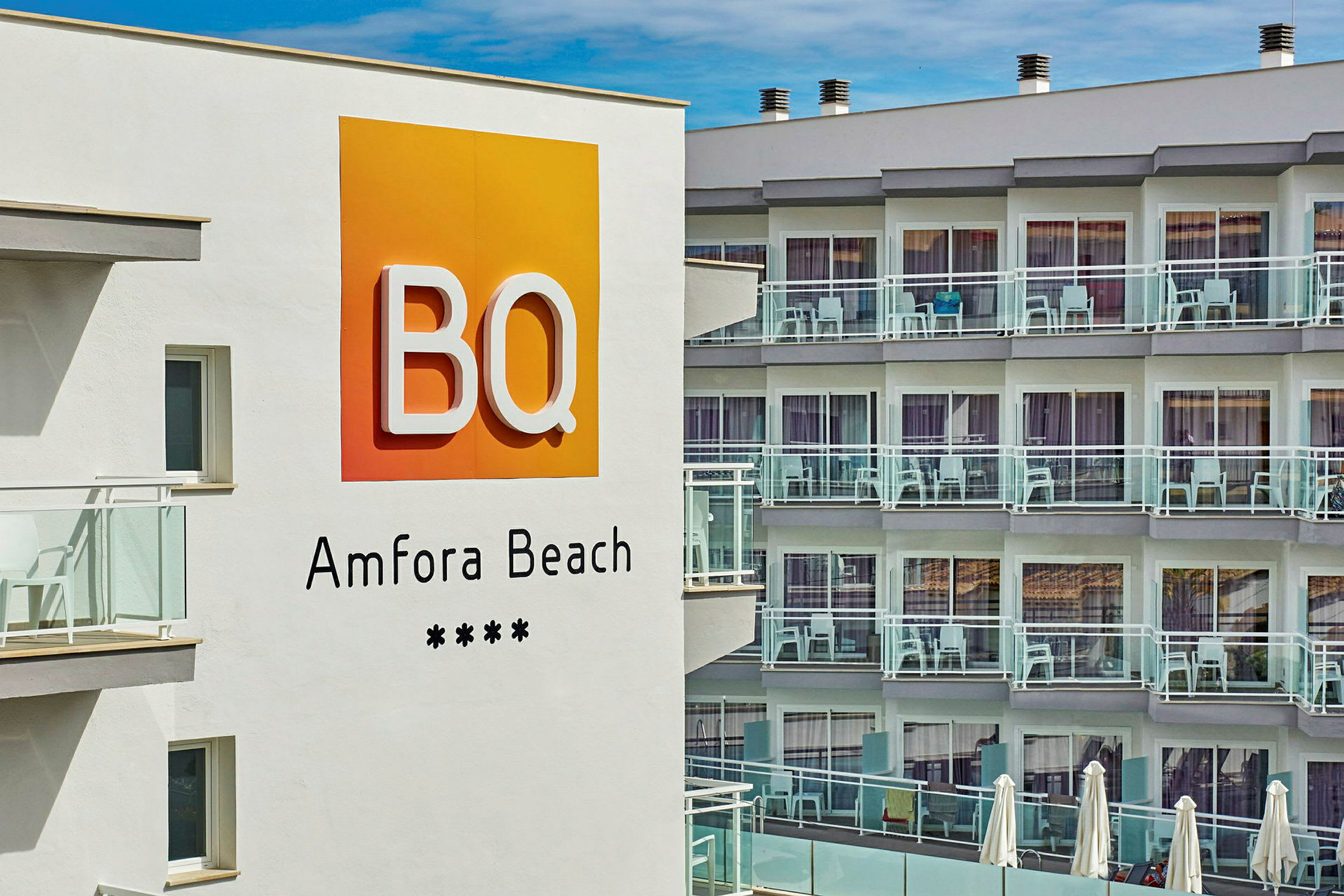 Hotellskilt med teksten "BQ Amfora Beach" foran en bygning med balkonger. (AI-generert tekst)