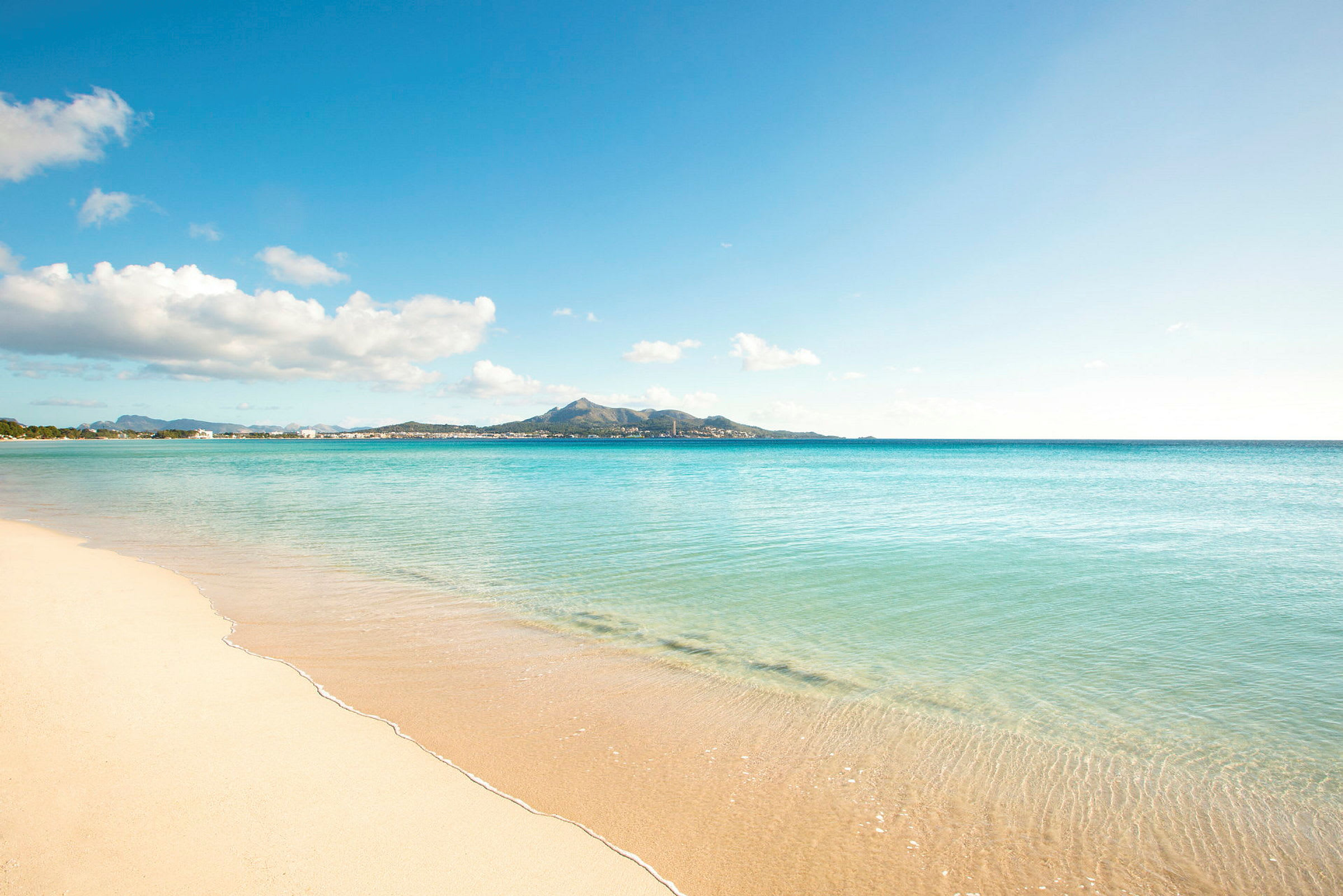 Bilde av en sandstrand med turkist vann under en blå himmel. (AI-generert tekst)