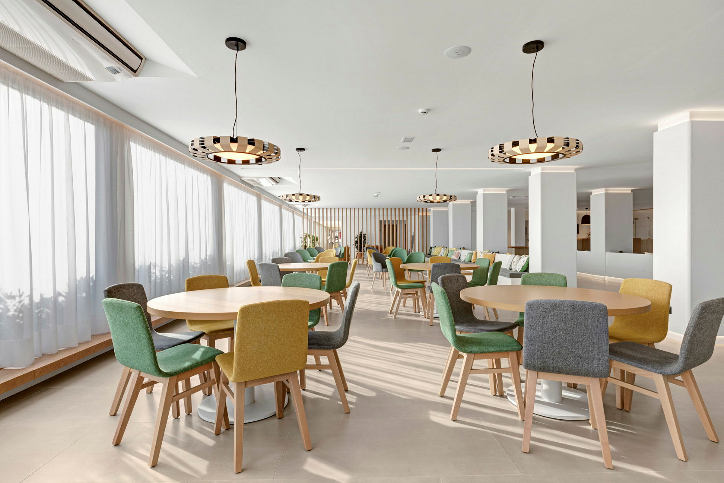 En restaurant med runde bord og stoler i forskjellige farger. (AI-generert tekst)