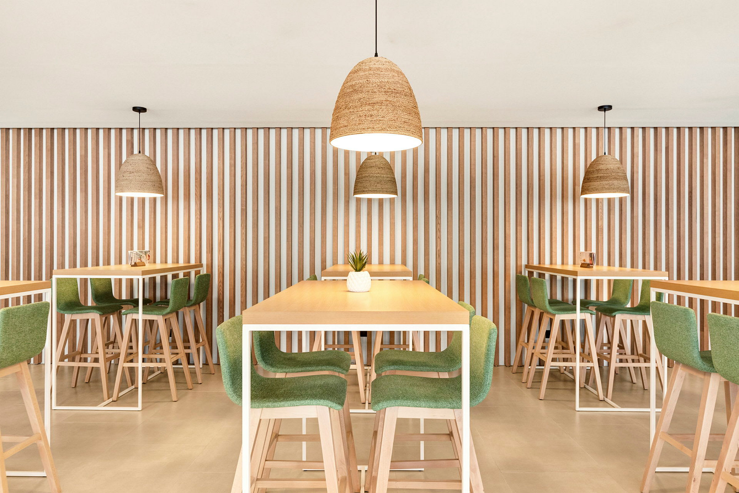 Bilde av moderne restaurantinteriør med bord og stoler i tre og grønt, og hengende lamper. (AI-generert tekst)