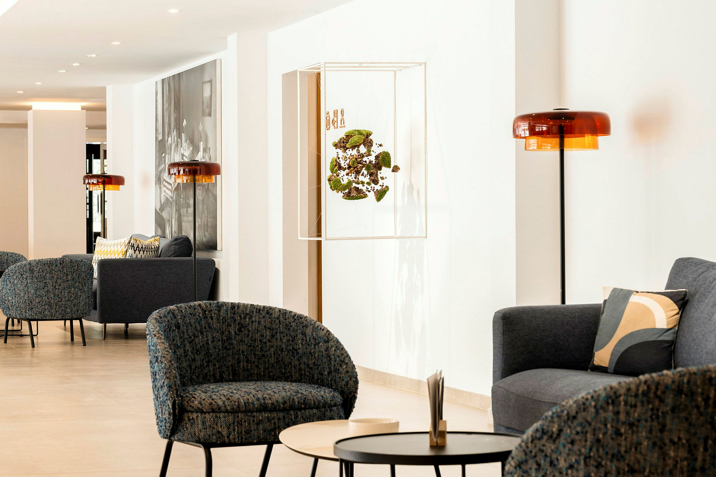 En moderne lounge med lenestoler, sofaer og bord i et lyst innemiljø. (AI-generert tekst)