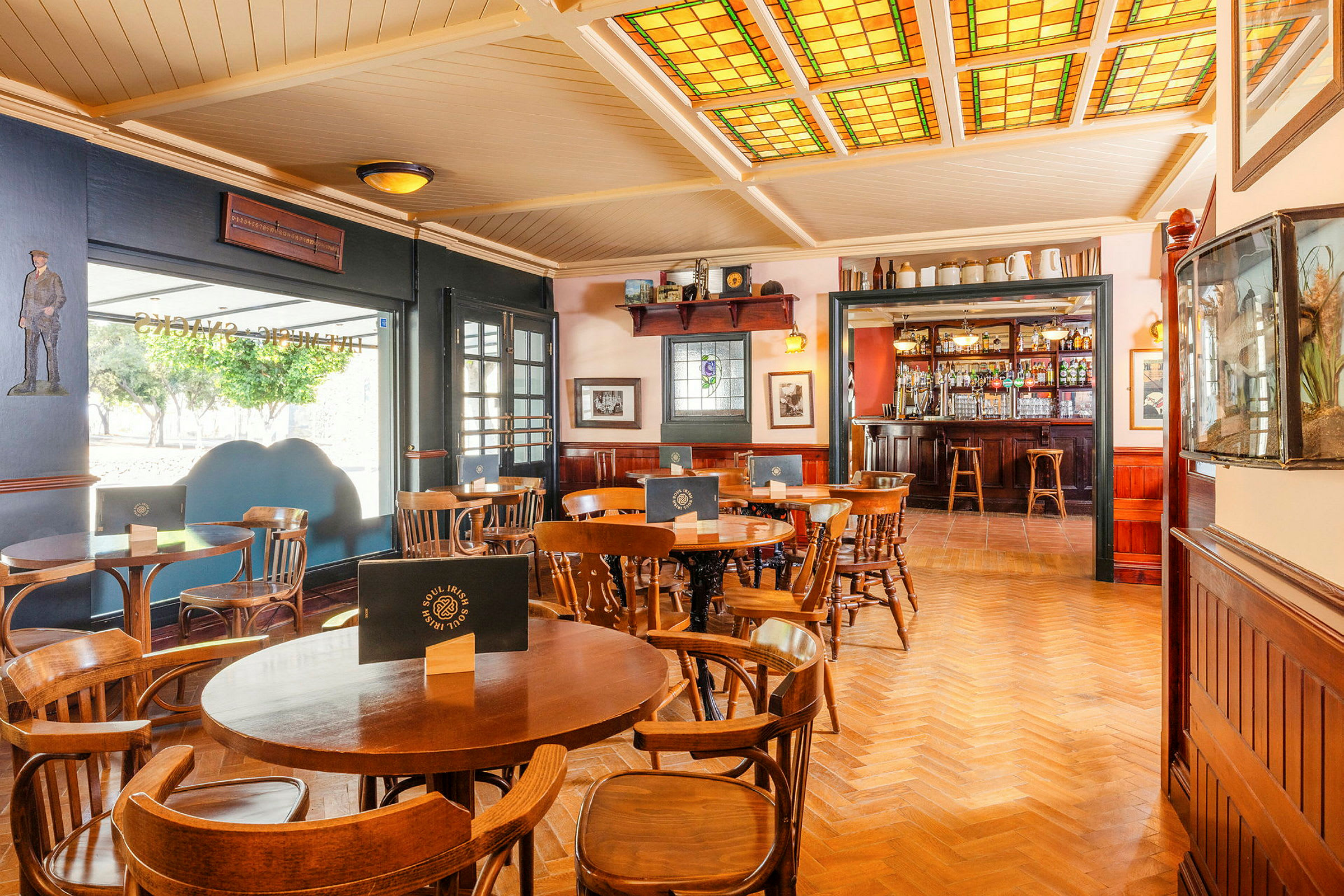Interiør av en pub med trestoler og bord samt en bar i bakgrunnen. (AI-generert tekst)