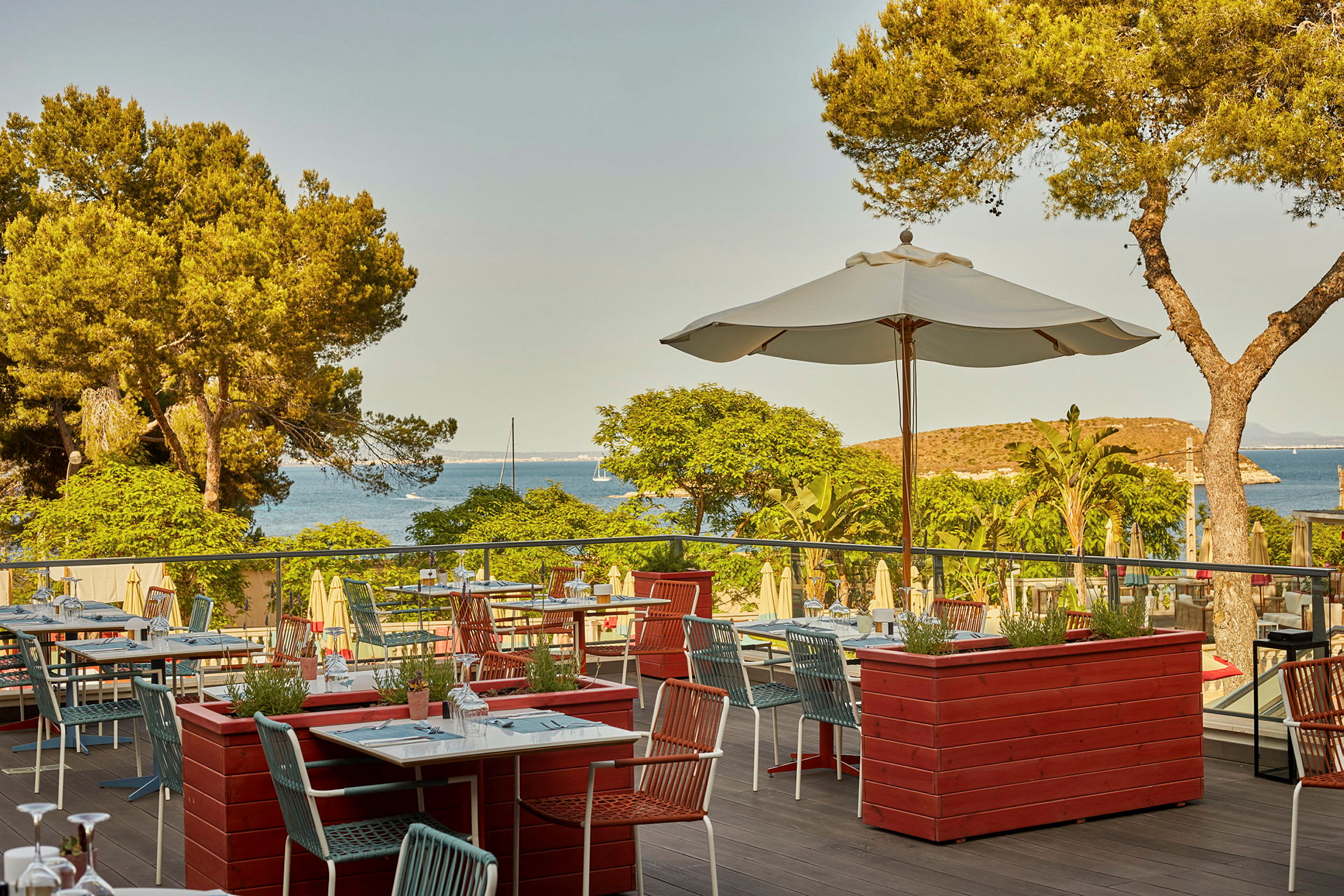 En terrasse restaurant med utsikt over havet og furuskog. (AI-generert tekst)