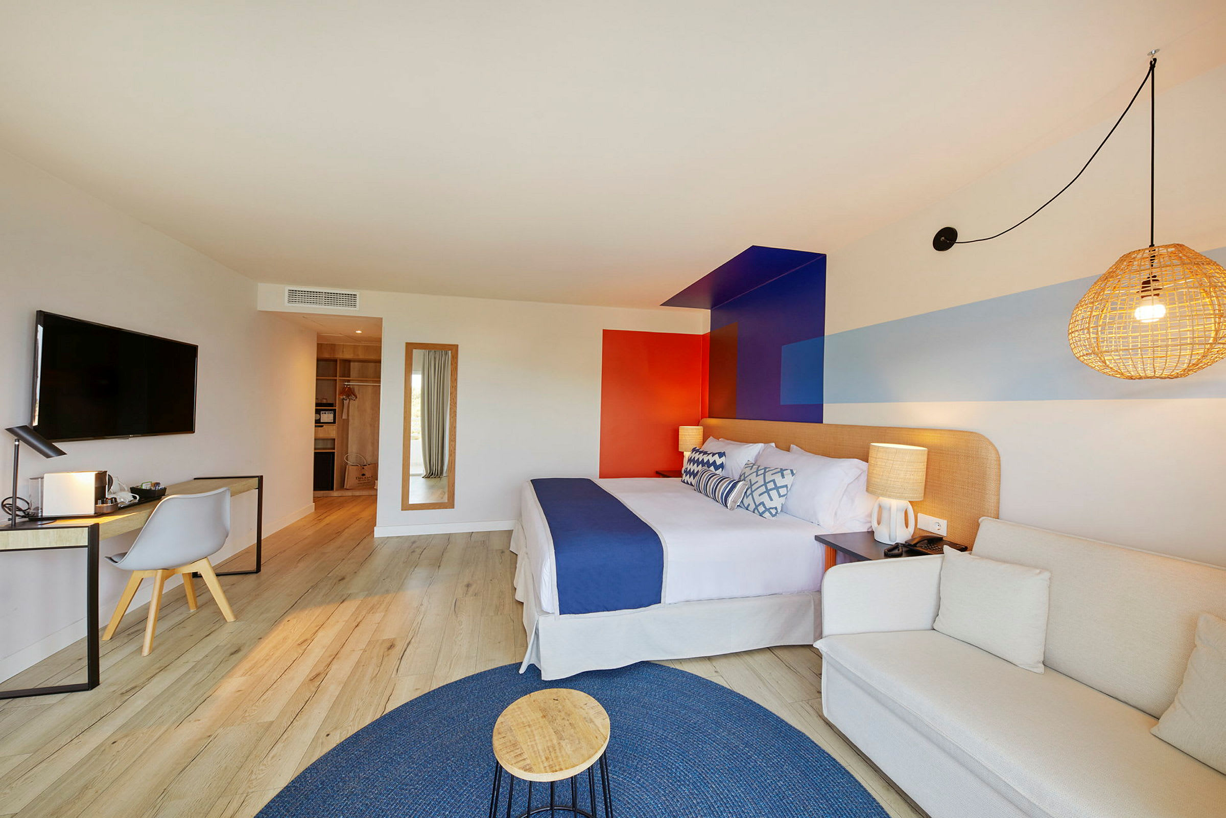 Et moderne hotellrom med en komfortabel seng, en skrivebordkrok og en sittegruppe, dekorert med fargerike detaljer. (AI-generert tekst)