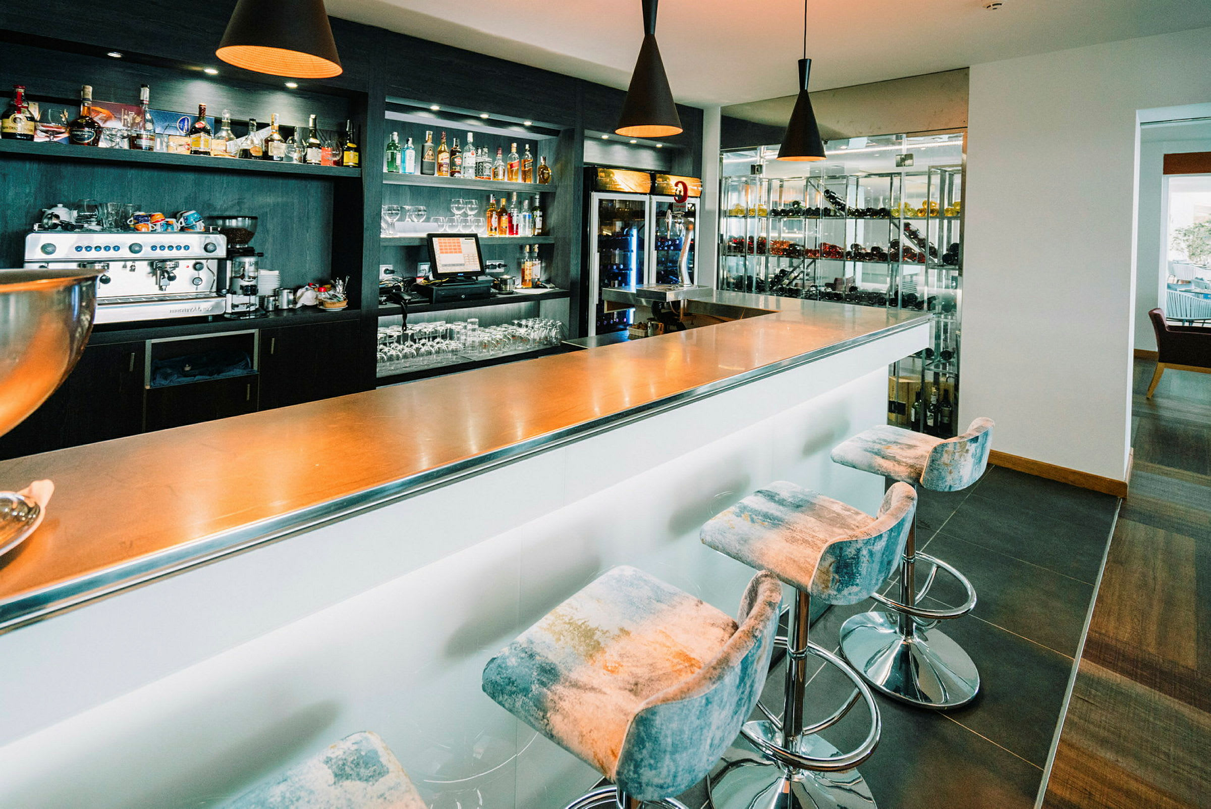 Bilde av en moderne bar med høye stoler og en metallisk bardisk. (AI-generert tekst)