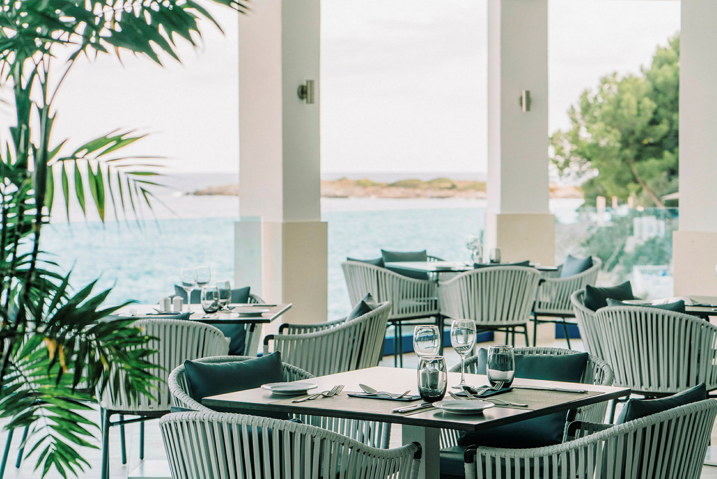 En utendørsrestaurant med utsikt over havet og vegetasjonen. (AI-generert tekst)