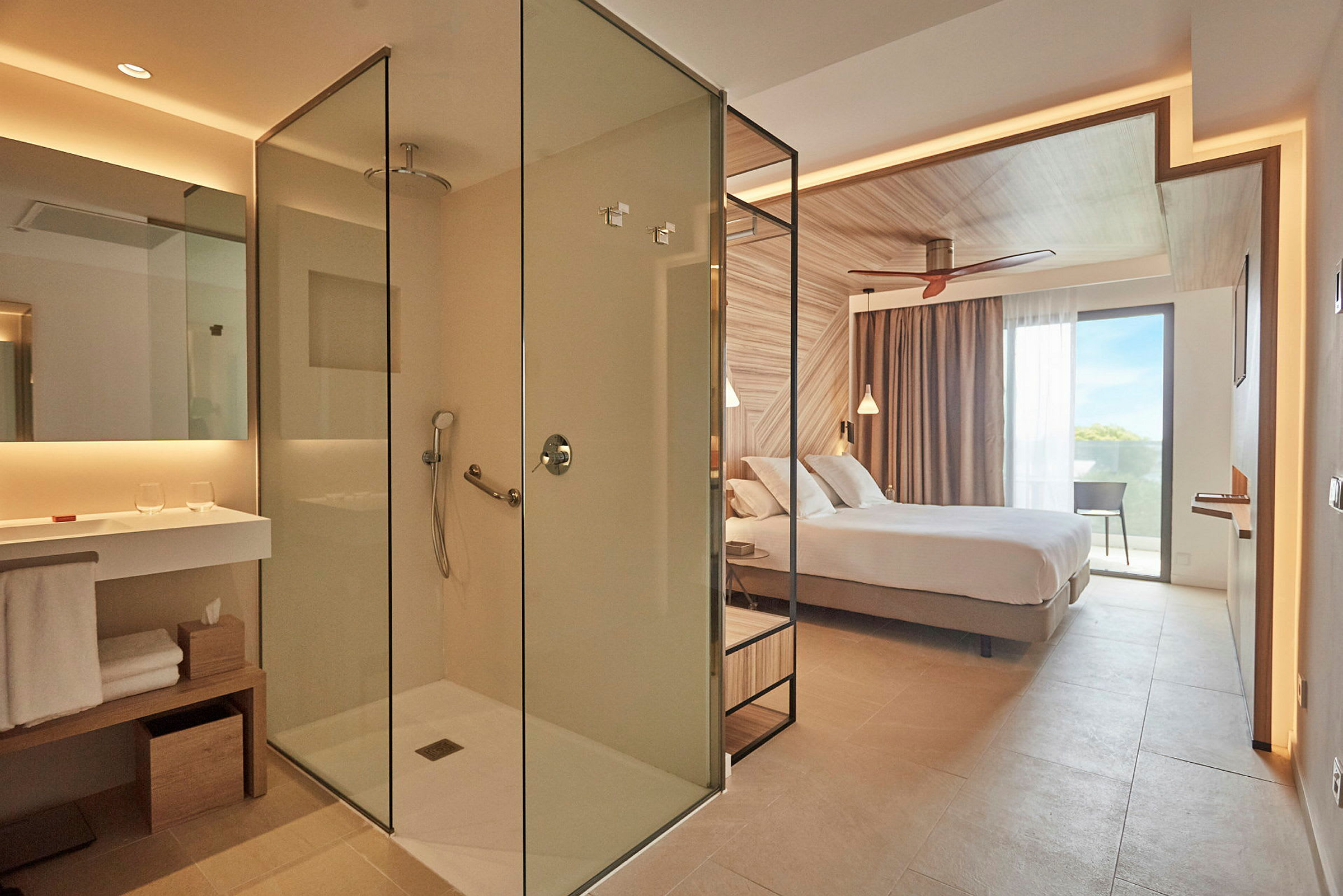 Et moderne hotellrom med en glasdusj og et soveområde med en dobbeltseng. (AI-generert tekst)