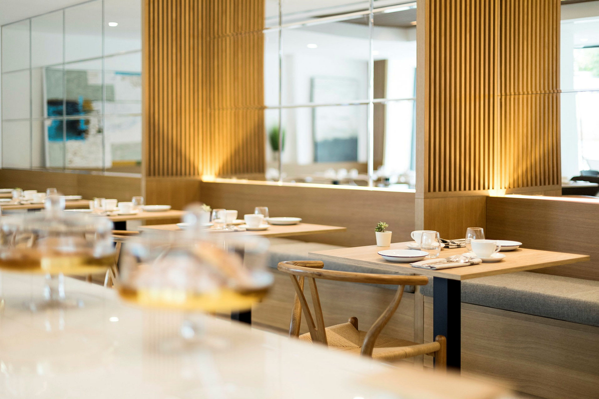 Restaurant med moderne møbler og trepaneler, dekket bord med servise. (AI-generert tekst)