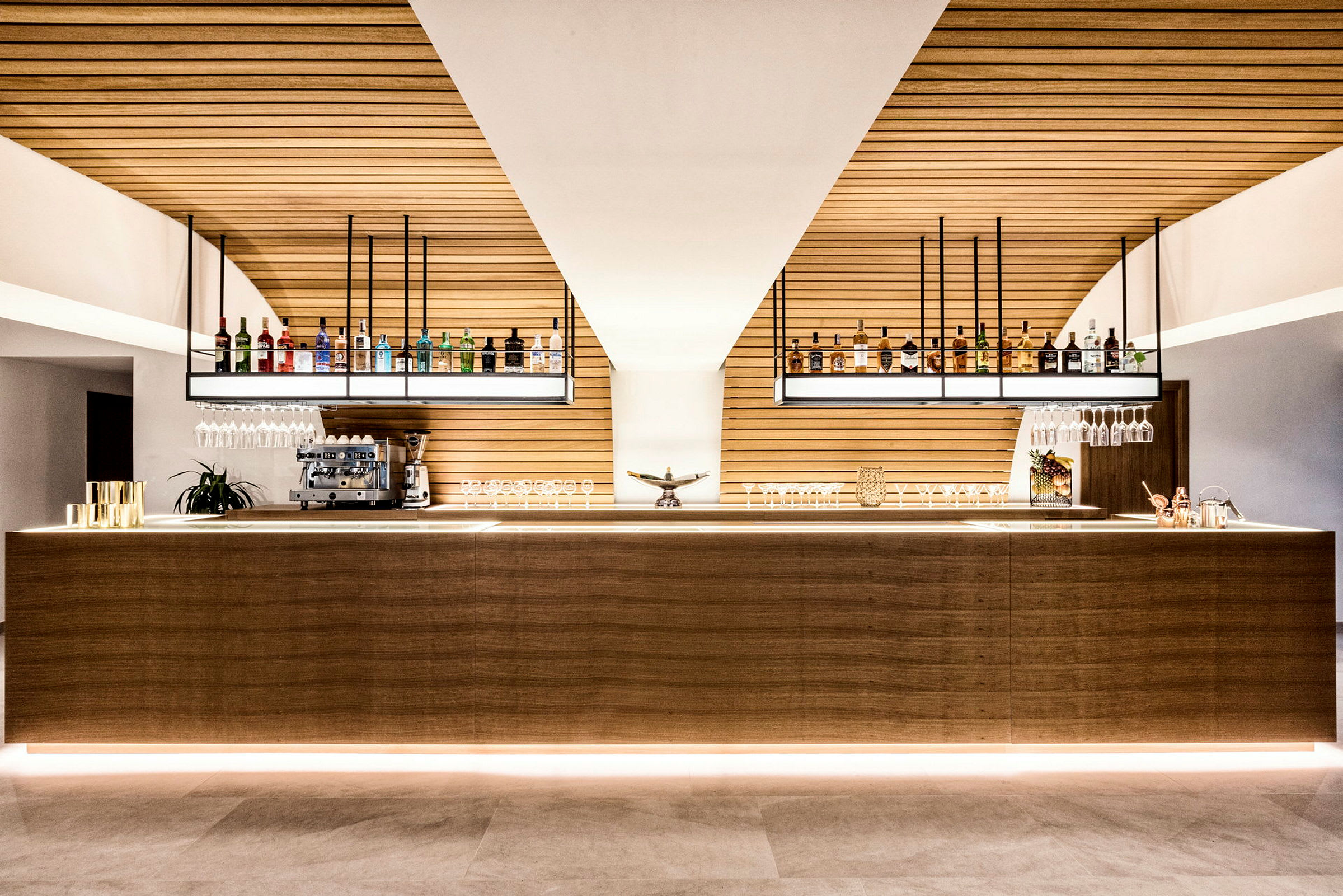 En stilfull og moderne bar med flasker og glass plassert på en trebar. (AI-generert tekst)