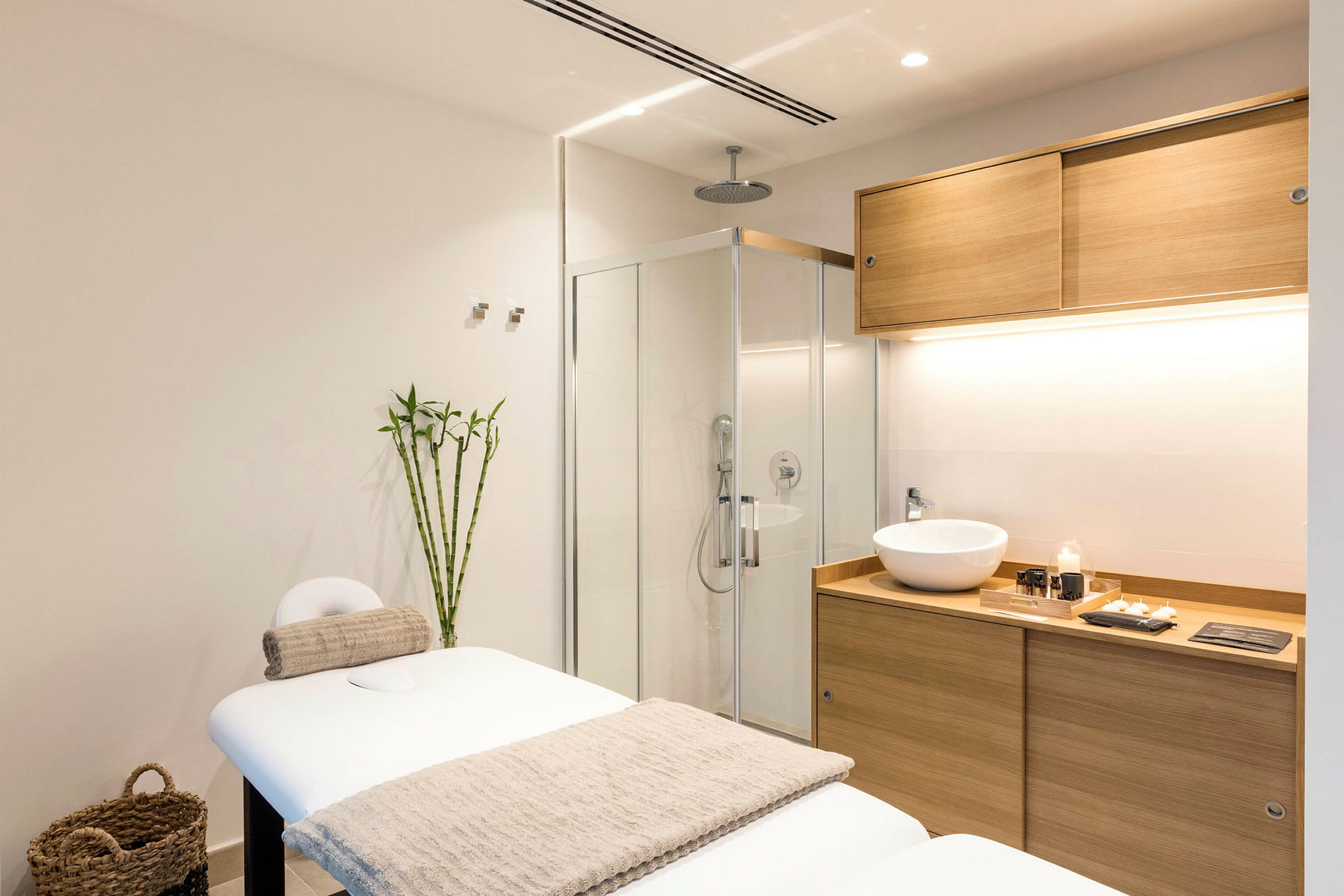 Et moderne spa-rom med en massasjebenk, bambusdekorasjon og en servant i treinnredning. (AI-generert tekst)