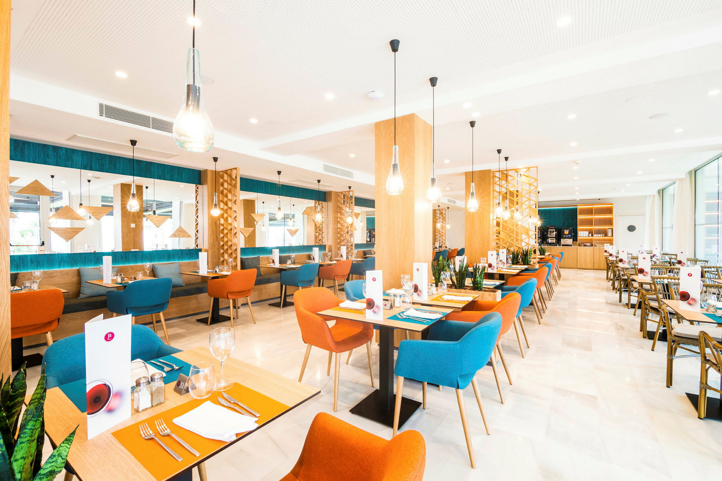 Bilde av en moderne restaurant med fargerike stoler, trebord og dekorative lysarmaturer. (AI-generert tekst)