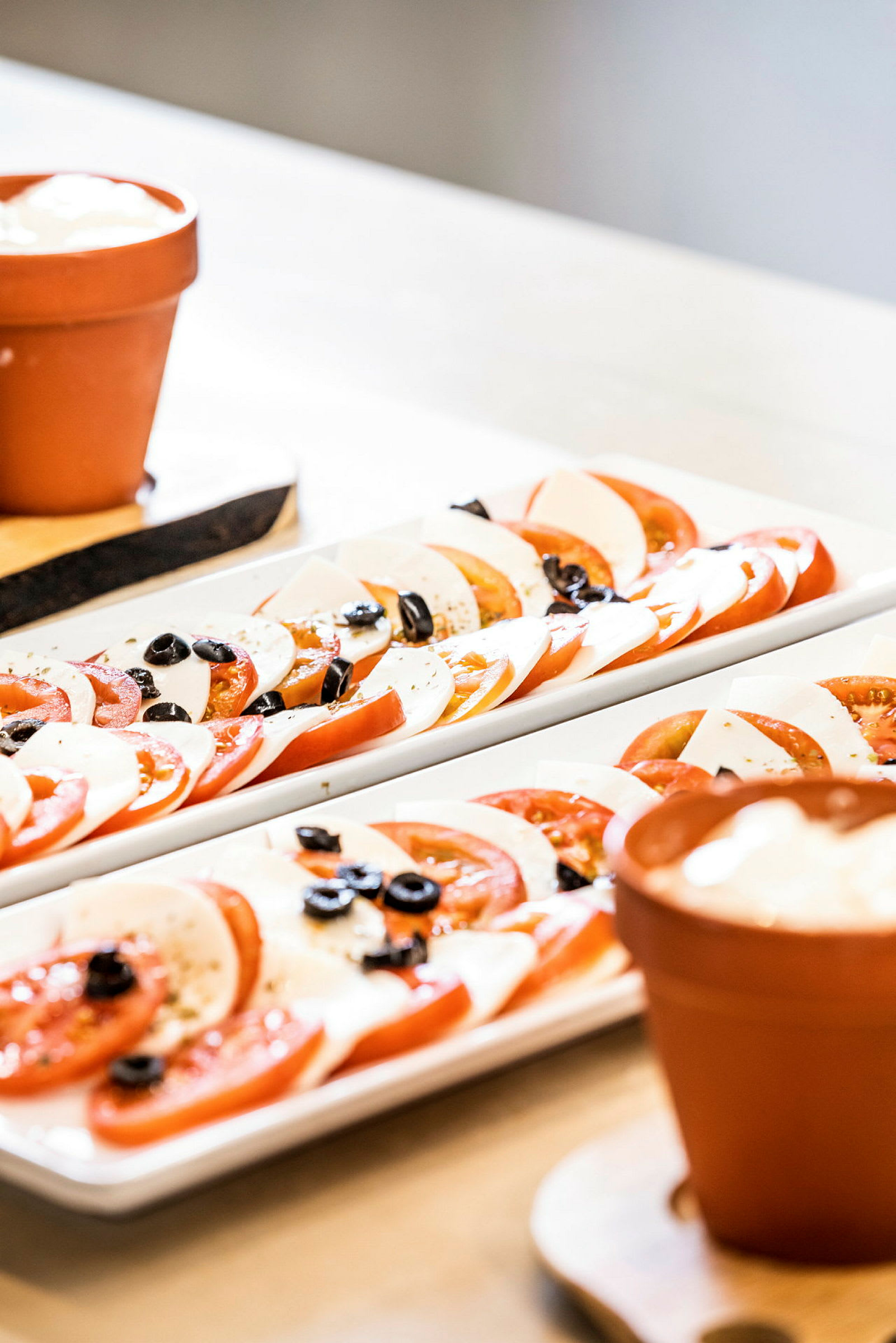 Nærbilde av tallerkener med skivet tomat, mozzarella og oliven. (AI-generert tekst)