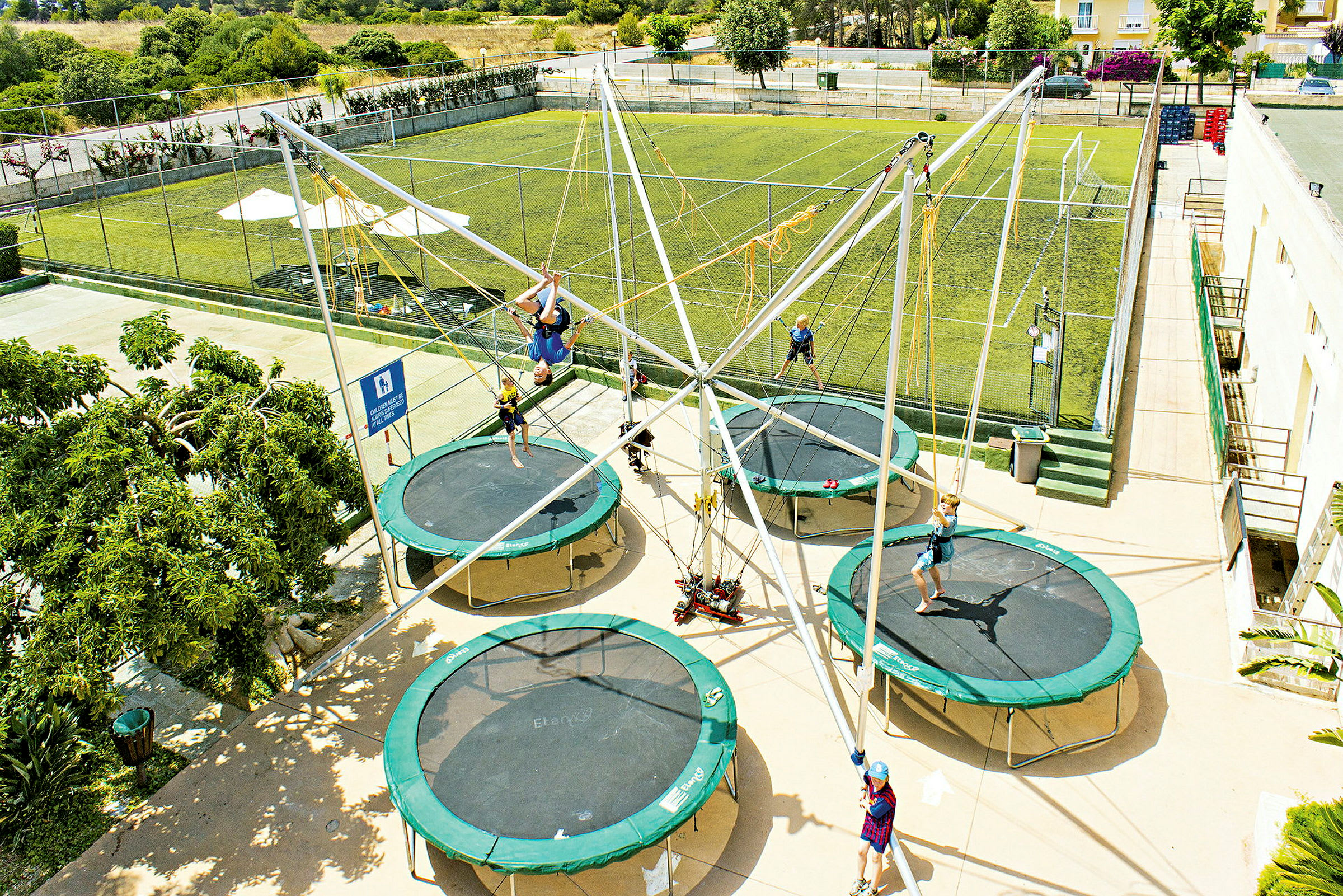 Flere personer hopper på trampoliner i en utendørspark. (AI-generert tekst)