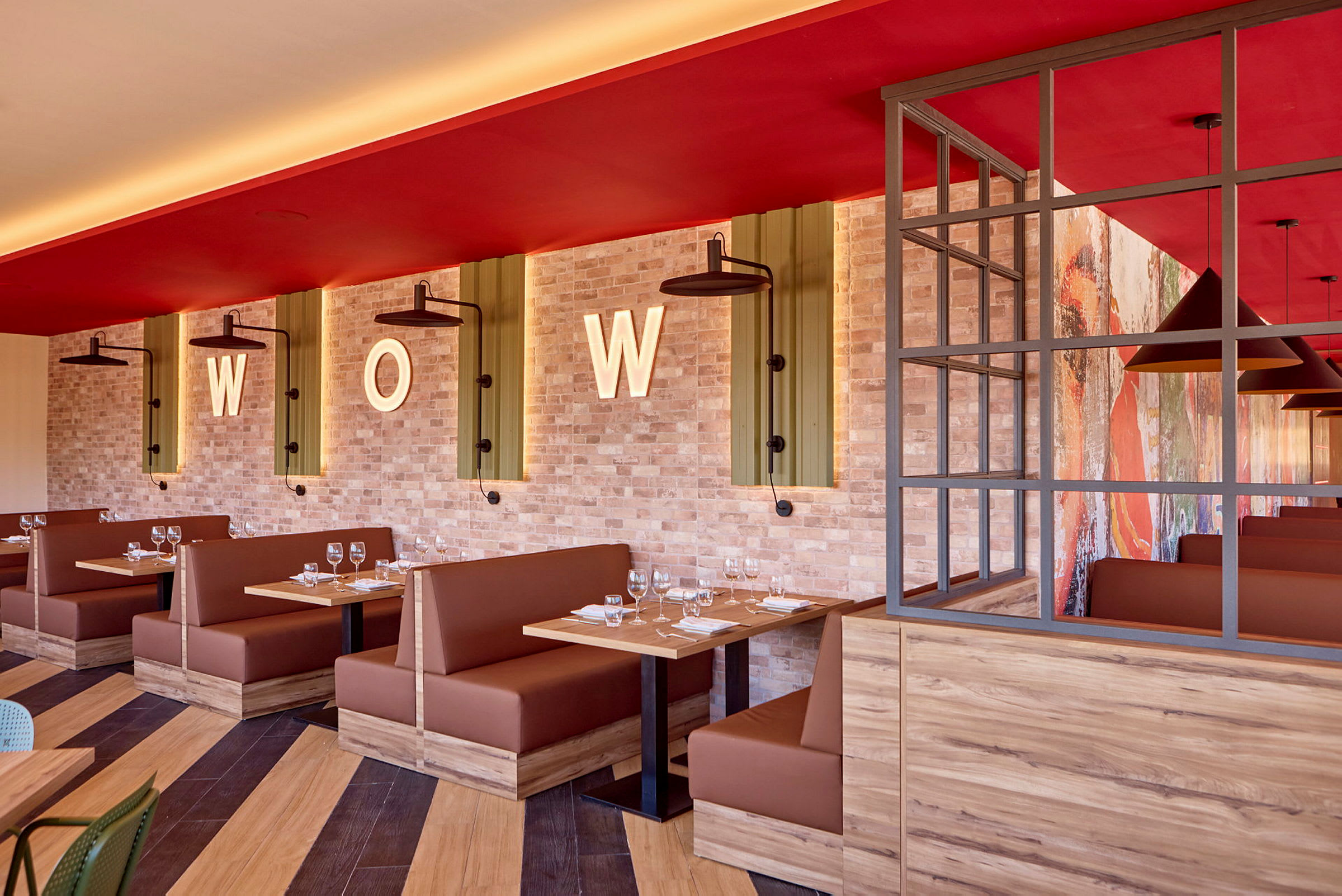 Restaurantmiljø med brune sitteplasser, trebord og murvegg dekorert med bokstavene "WOW". (AI-generert tekst)
