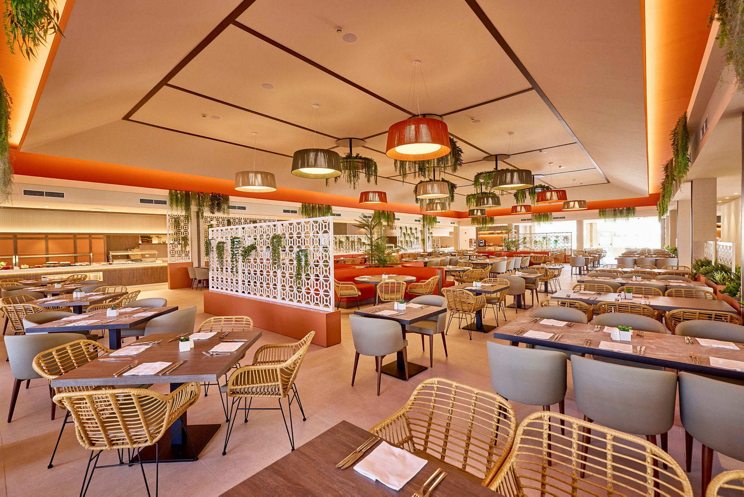 En lys restaurant med moderne møbler og dekor, inkludert hengende lamper og mye planter. (AI-generert tekst)
