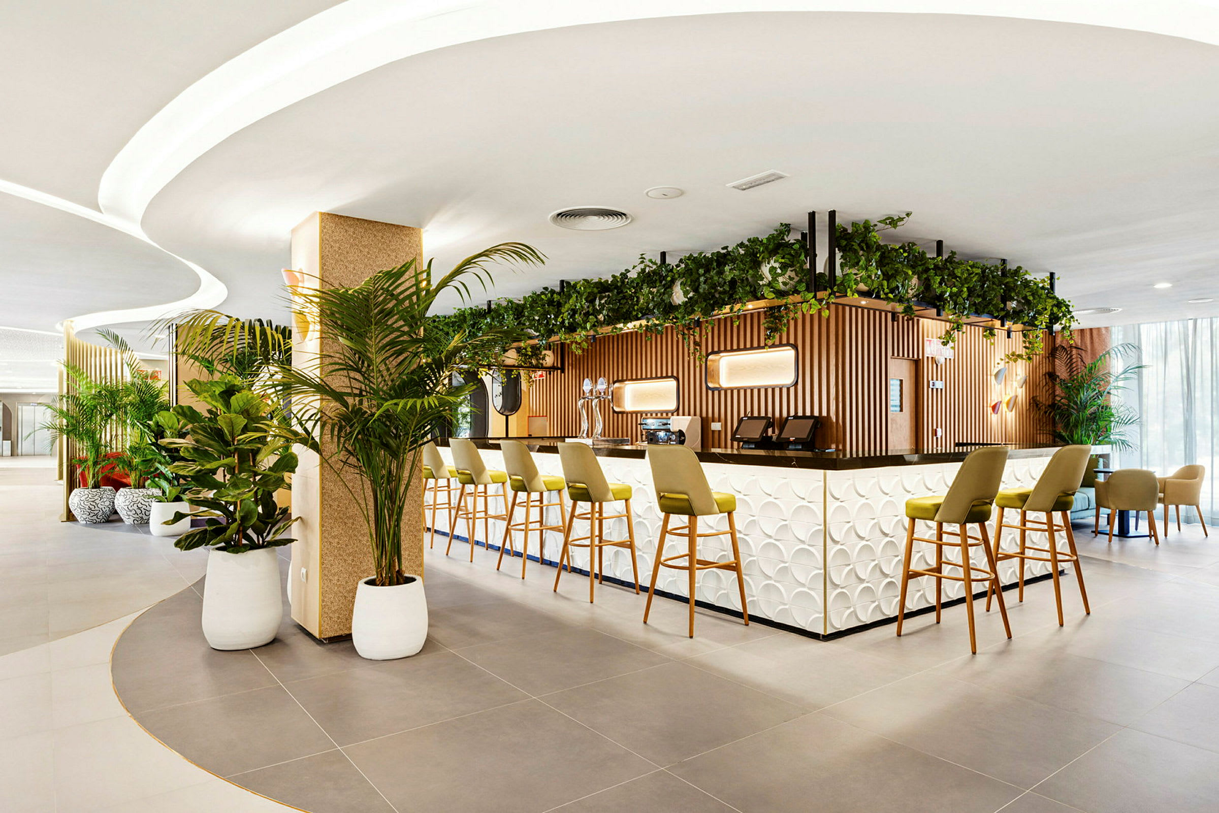 Bilde av en moderne hotellbar med en stilfull disk og grønne planter. Stoler er plassert ved bardisken. (AI-generert tekst)
