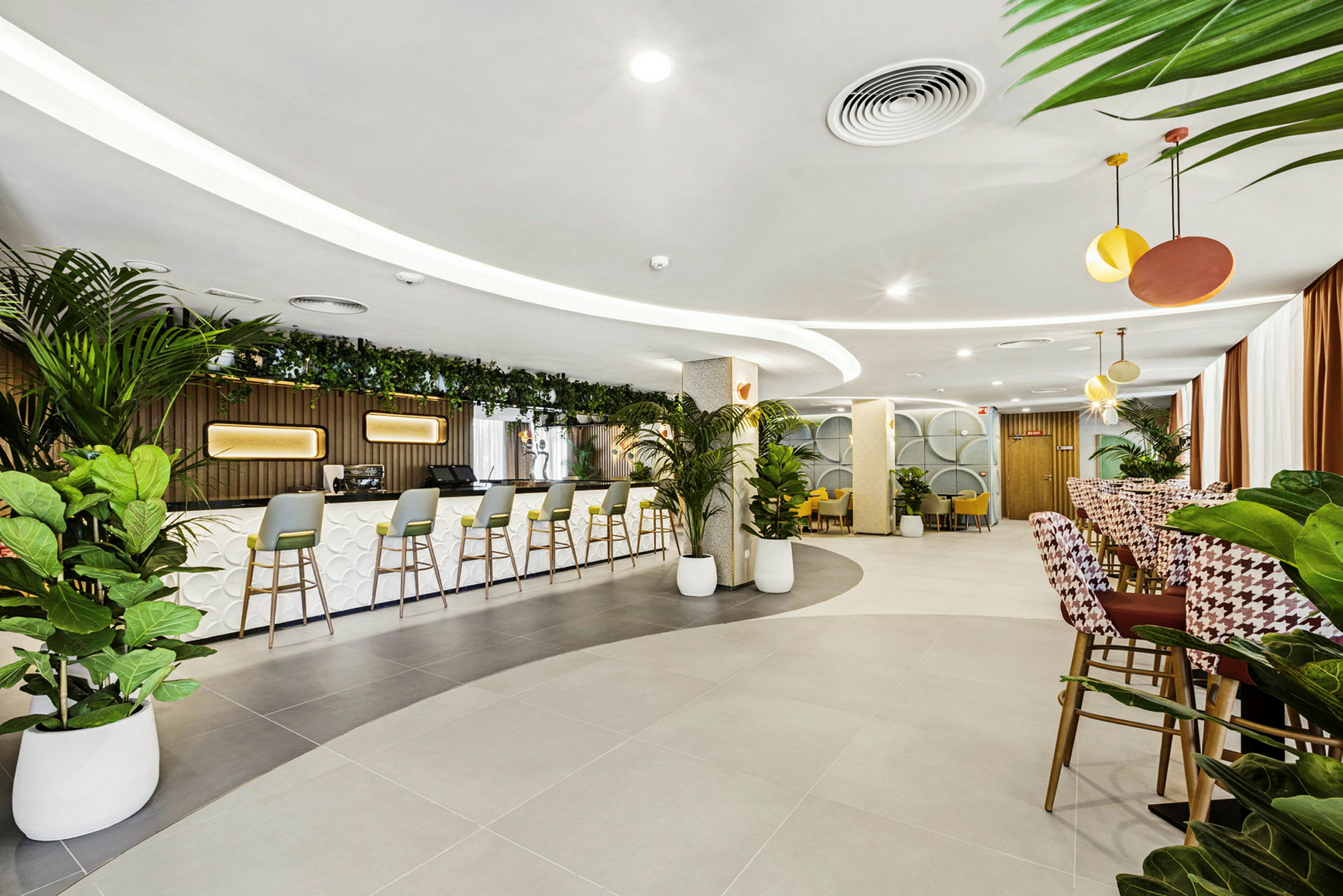 En moderne lounge med en bar og flere sitteplasser. Planter brukes som dekorasjon. (AI-generert tekst)