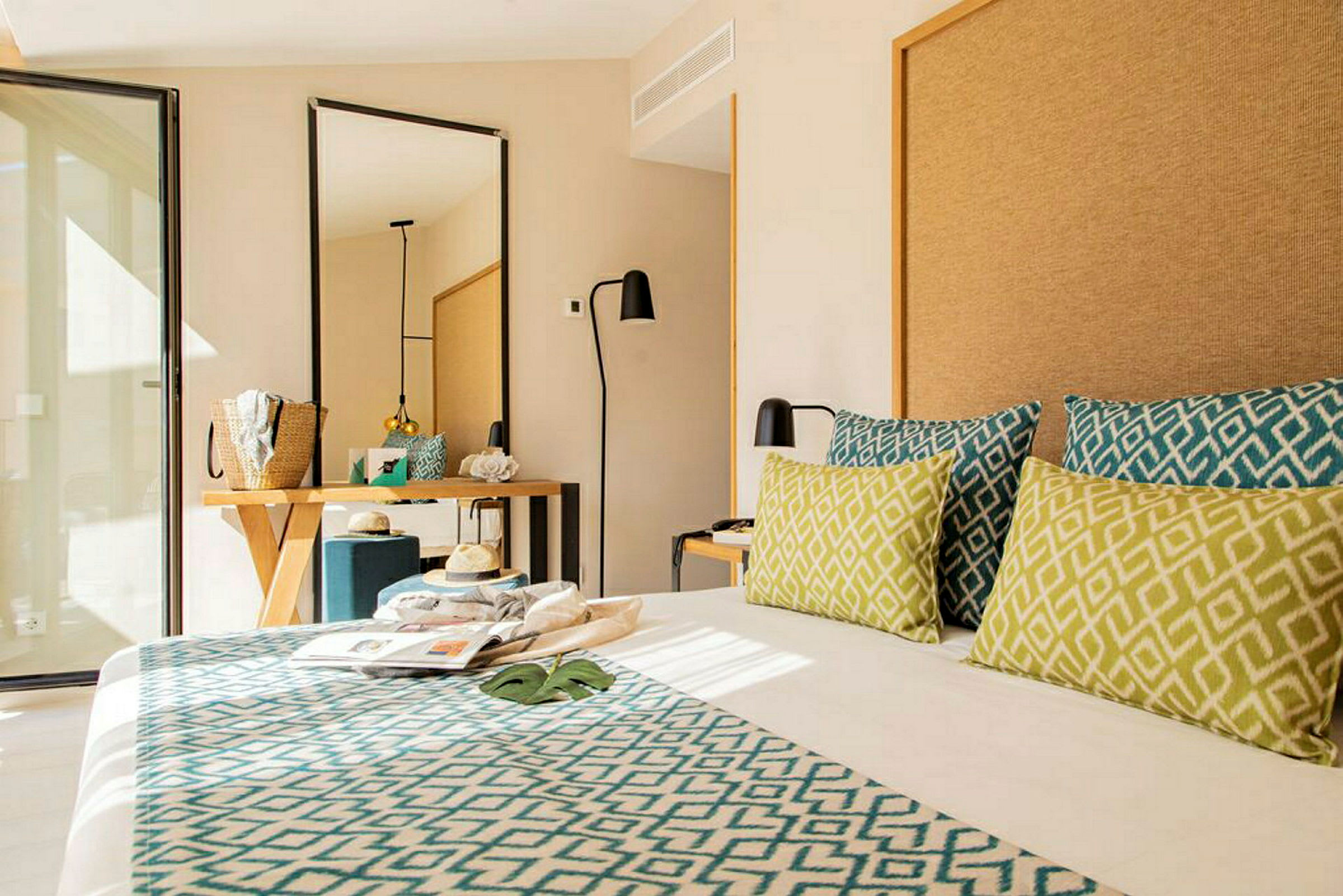 Hotellrom med moderne innredning, seng med dekorative puter, speil og skrivebord. (AI-generert tekst)