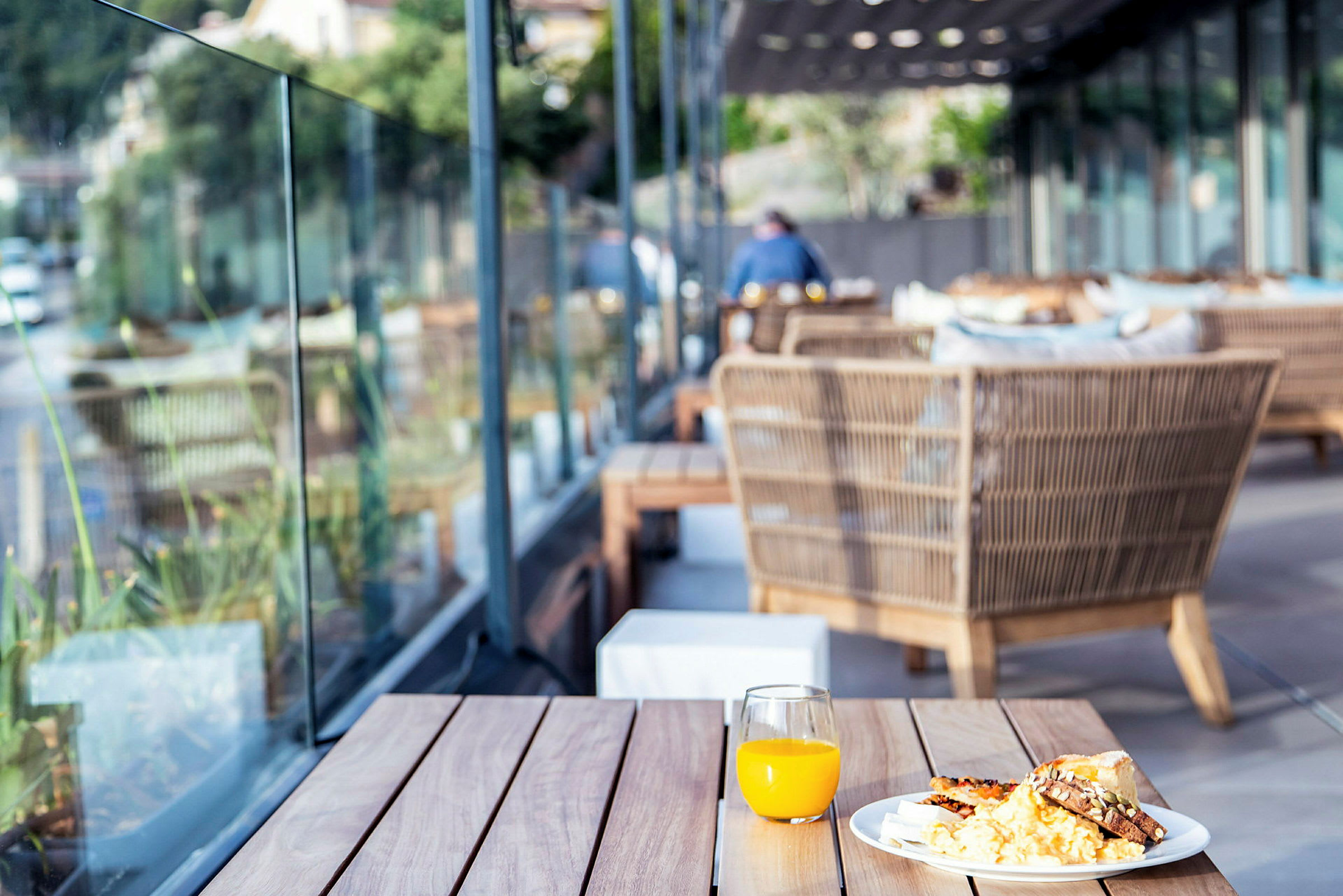 En tallerken med mat og et glass appelsinjuice på et bord utendørs. (AI-generert tekst)