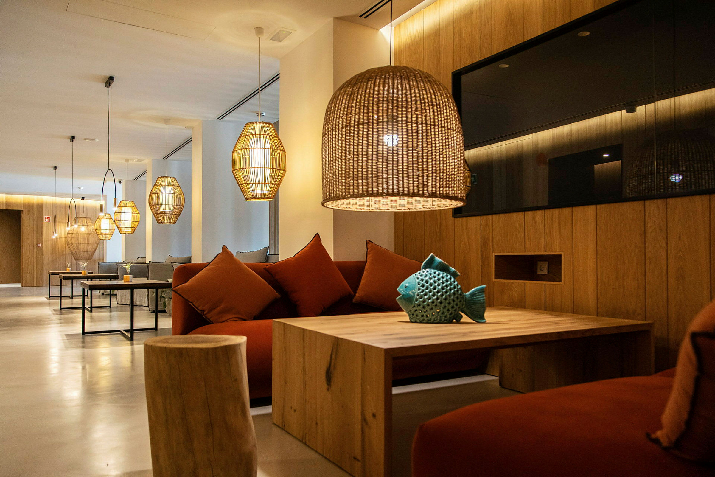 Moderne lounge med sofaer, trebord og hengende lamper. (AI-generert tekst)