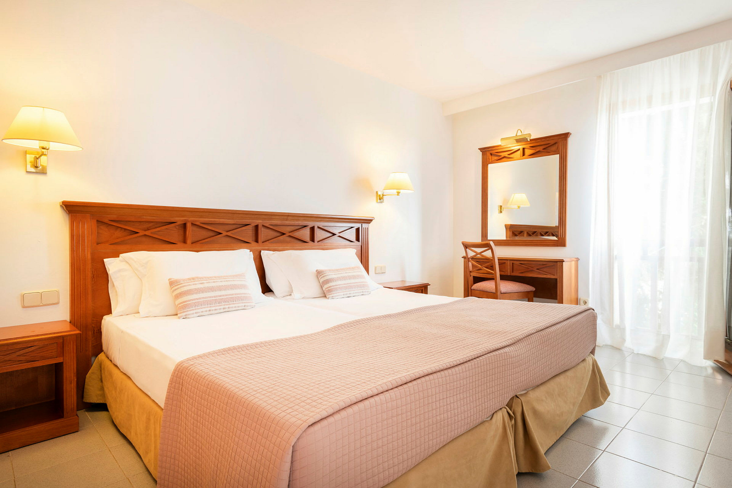 Hotellrom med dobbeltseng, nattbord og skrivebord med speil. (AI-generert tekst)