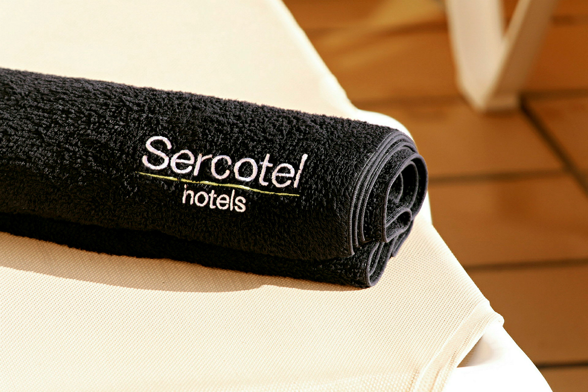 Et svart håndkle med teksten 'Sercotel hotels' brodert, plassert på en lys overflate. (AI-generert tekst)