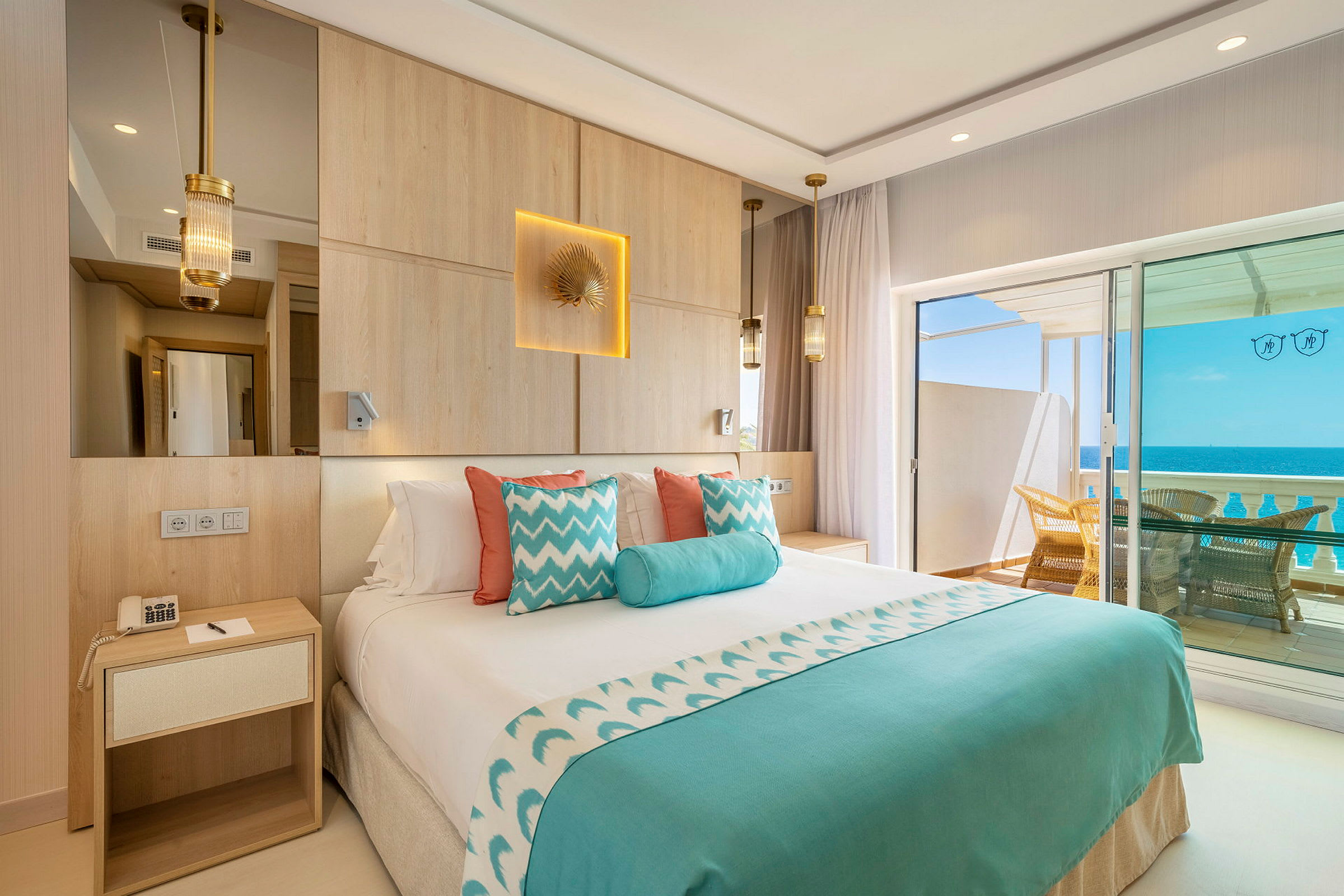 Hotellrom med dobbeltseng, dekorert i blått og hvitt, med utsikt over havet fra en balkong. (AI-generert tekst)