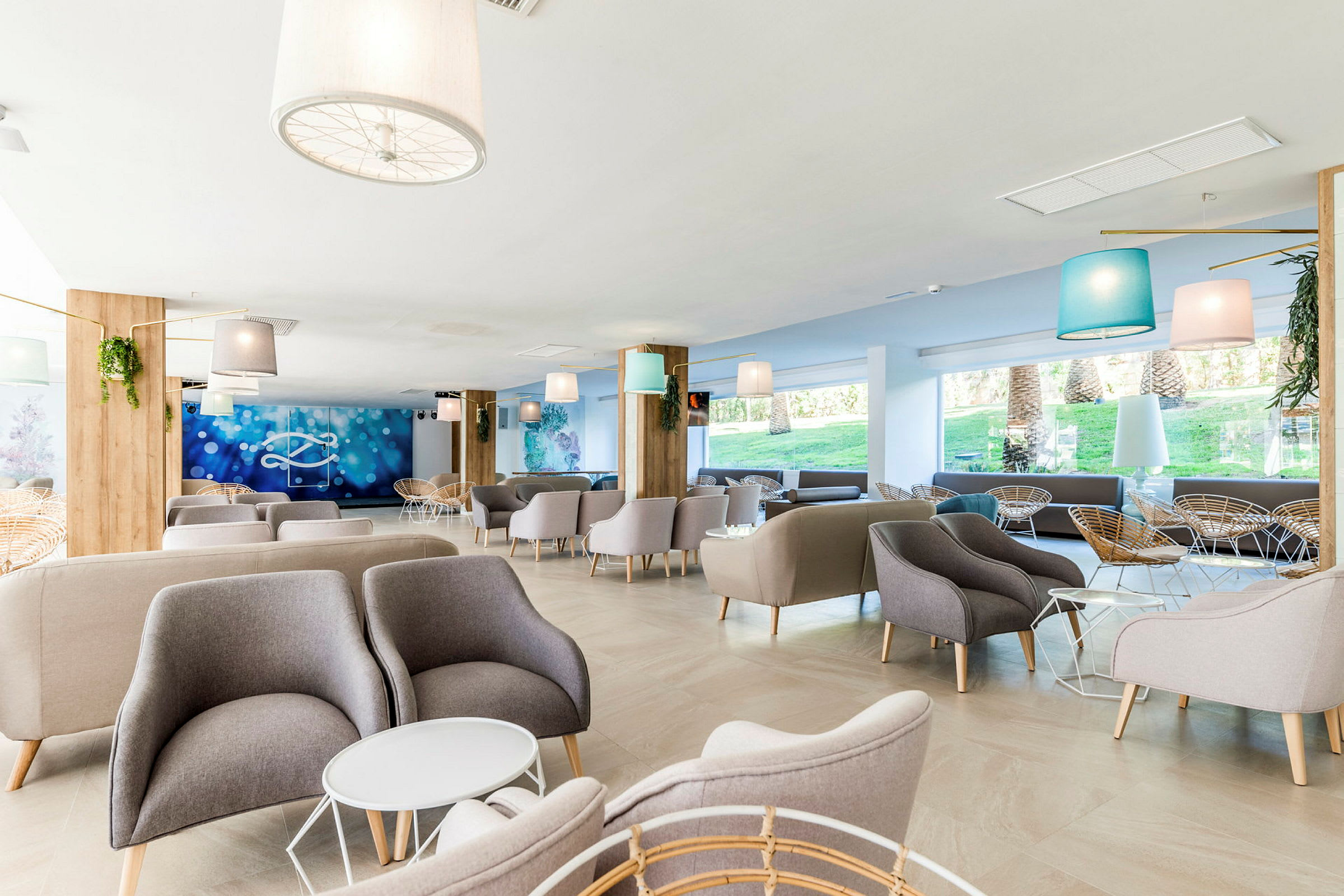 Bildet viser en lys og moderne hotellobby med komfortable lenestoler og sofaer, samt store vinduer som slipper inn dagslys. (AI-generert tekst)