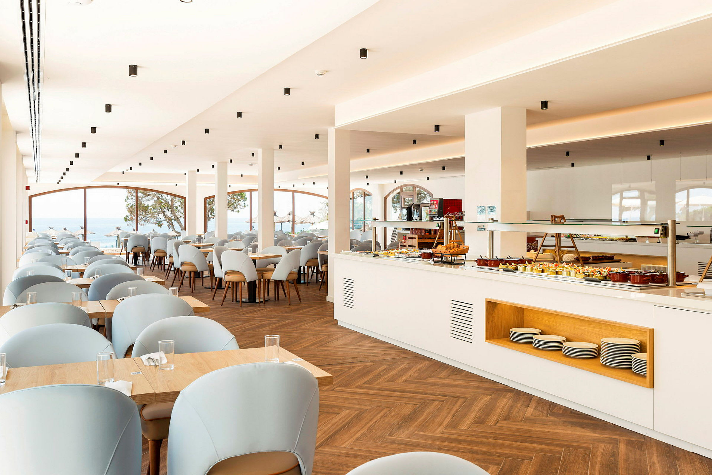 En lys restaurant med borde og stoler samt en buffé. (AI-generert tekst)