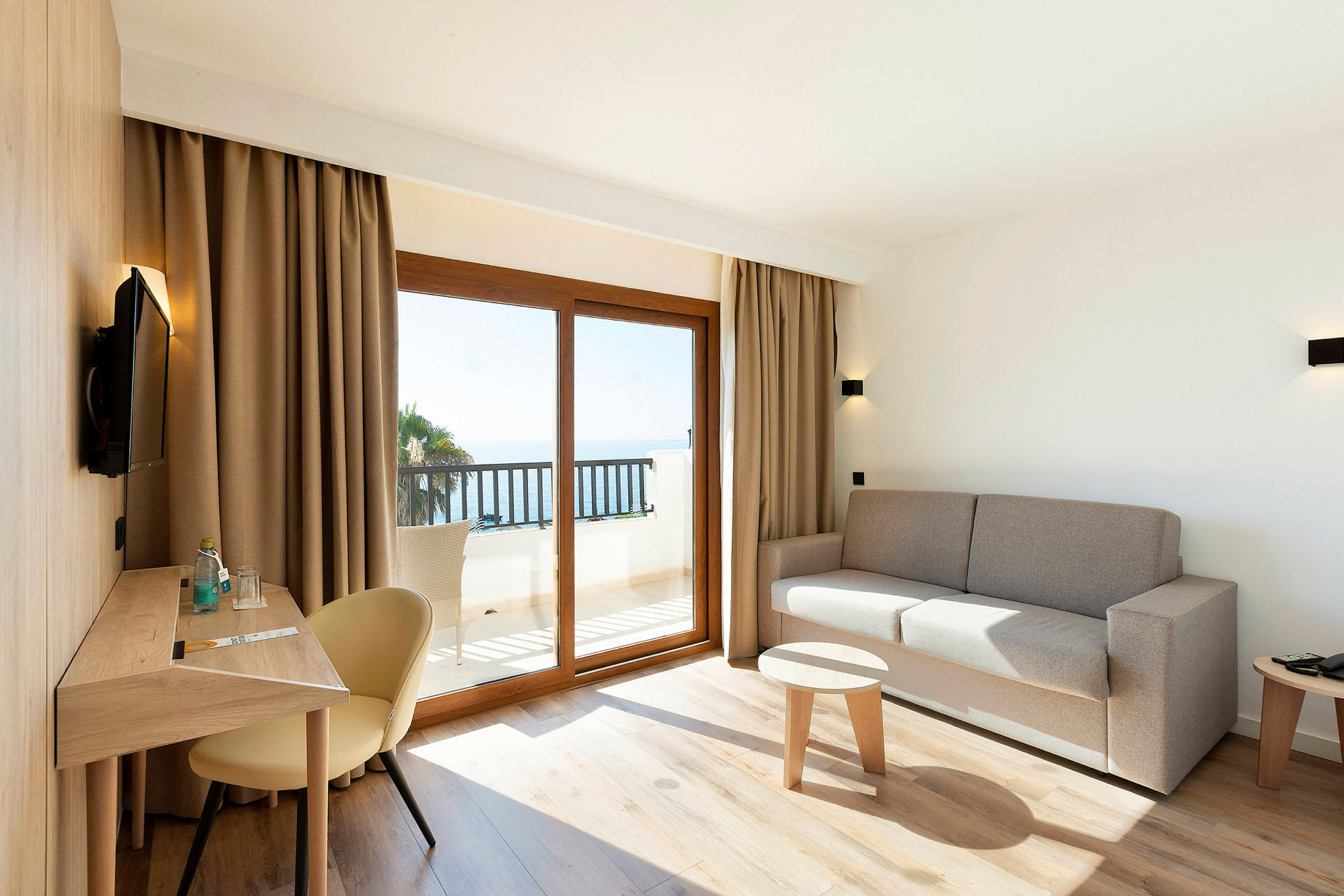 Moderne innredet hotellrom med sittegruppe og utsikt mot havet. (AI-generert tekst)