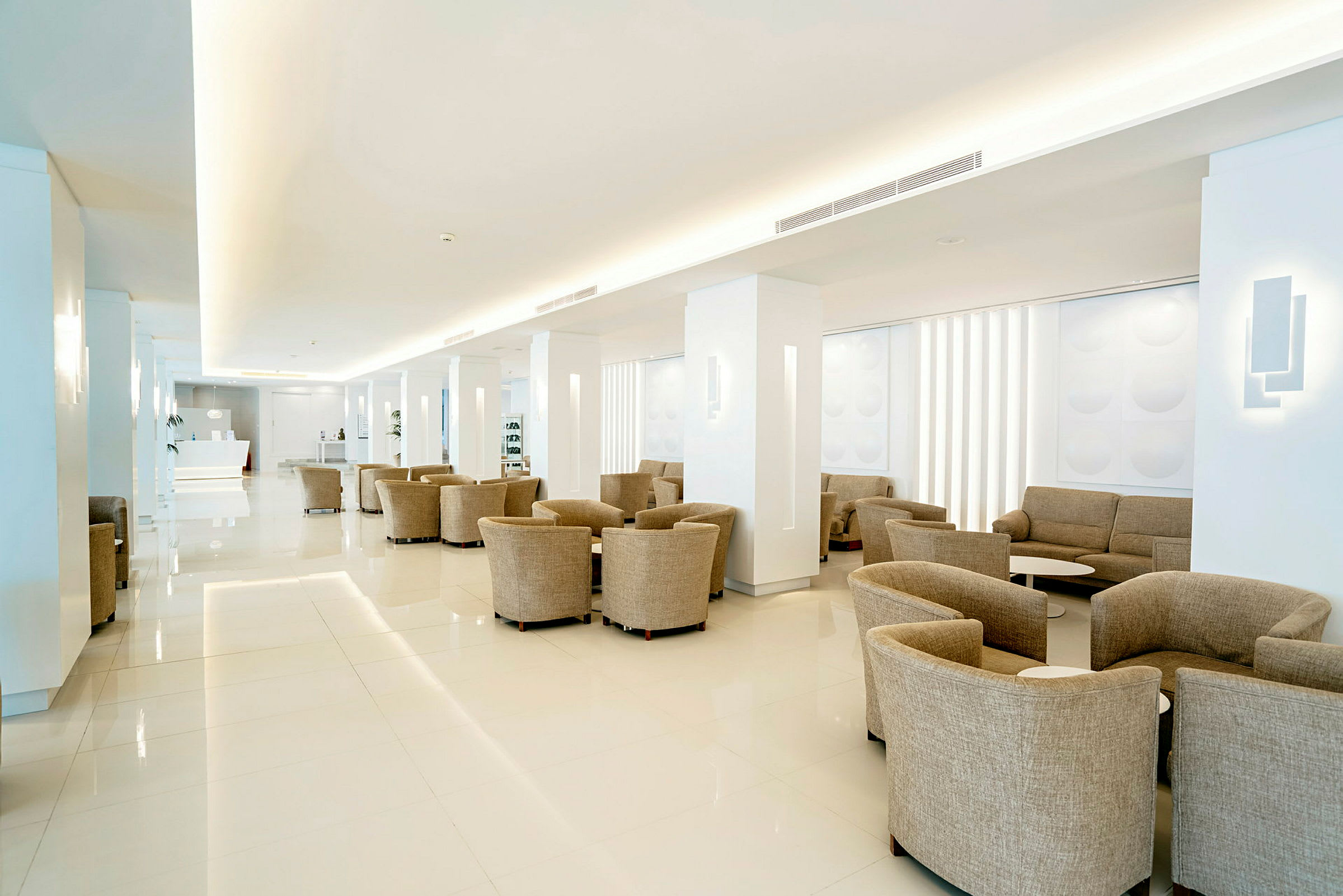 En romslig og lys hotellobby med beige sitteplasser. (AI-generert tekst)