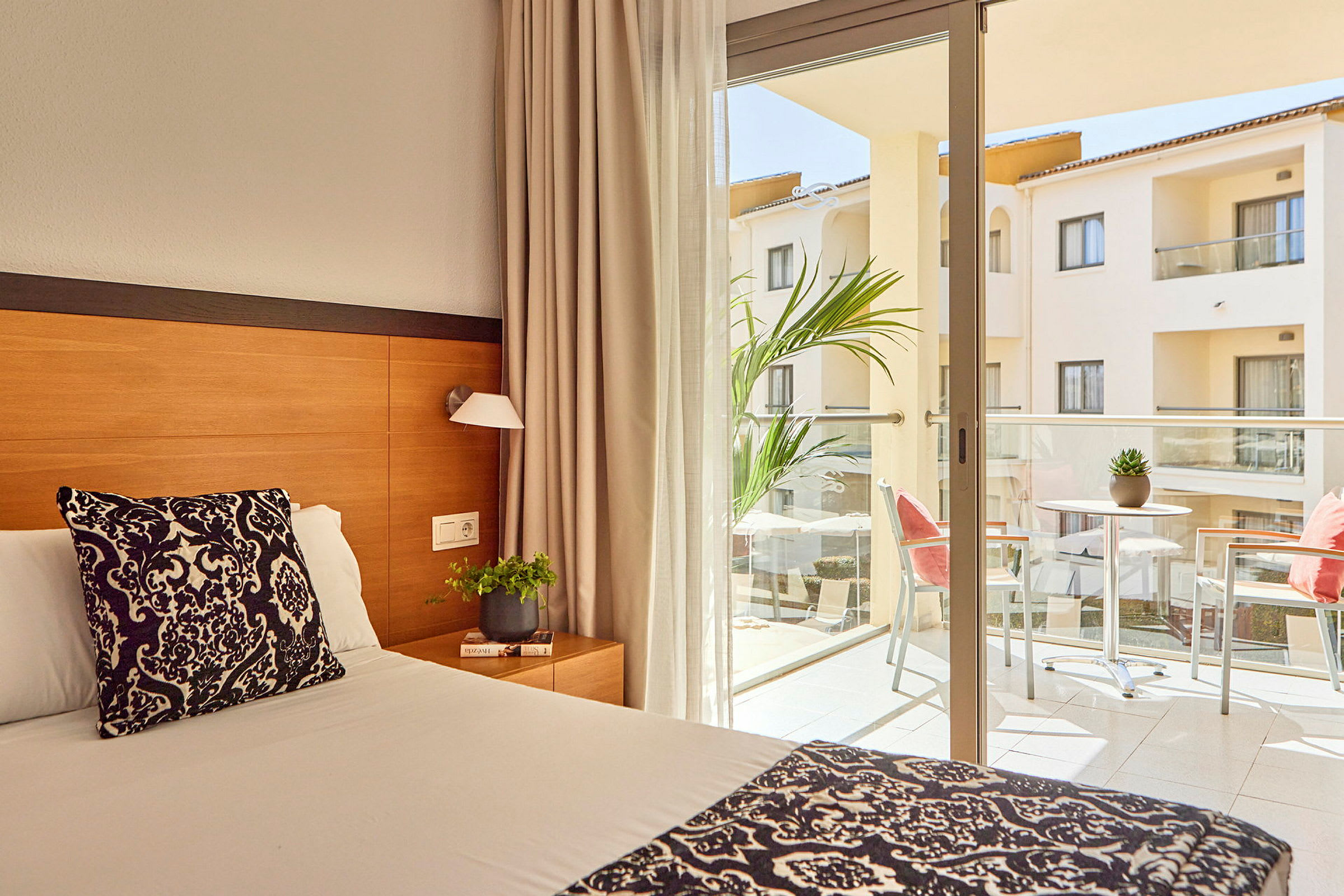 Hotellrom med seng og balkong med møbler. (AI-generert tekst)