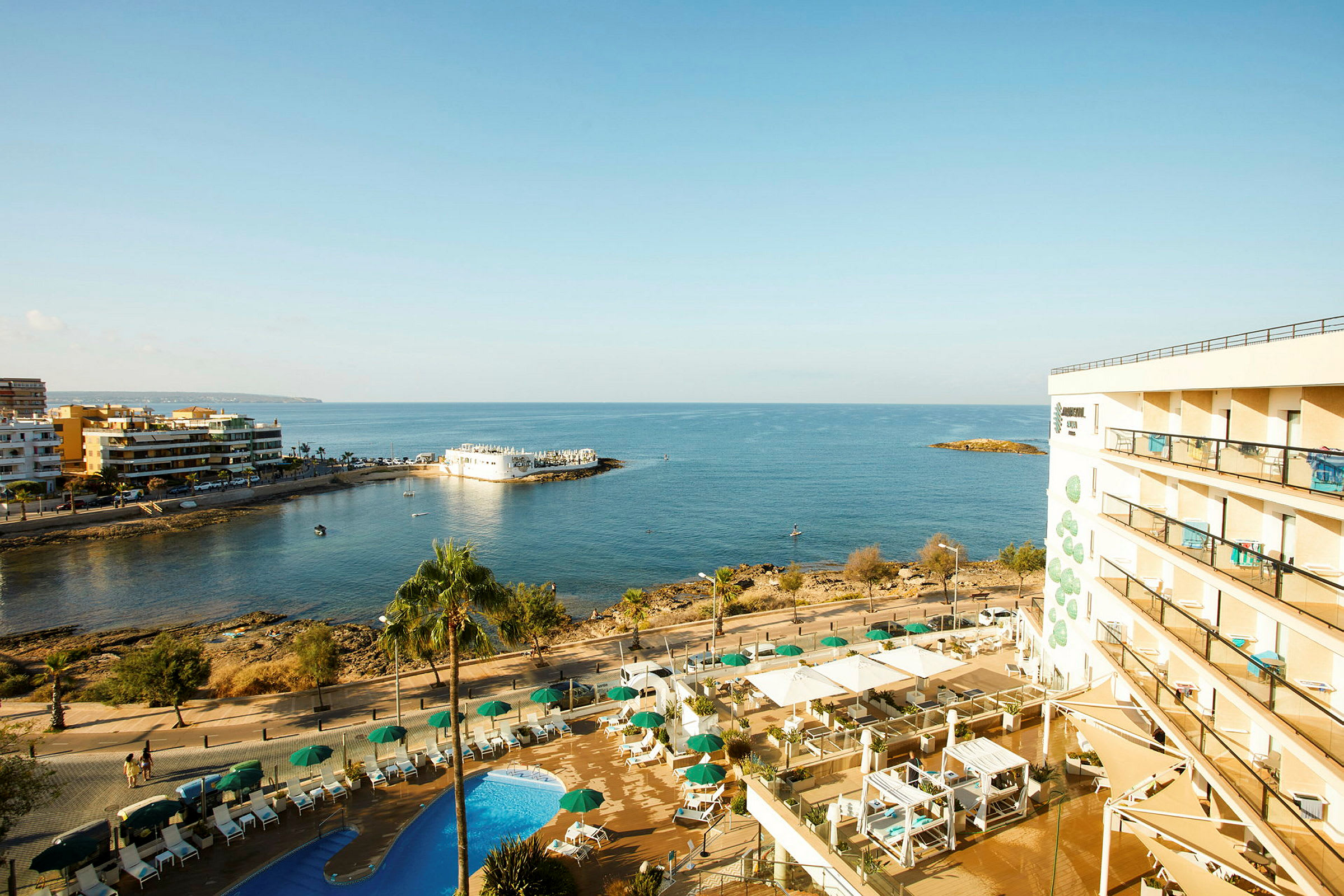 Hotellet med bassenger og utsikt over havet og kystlinjen. (AI-generert tekst)