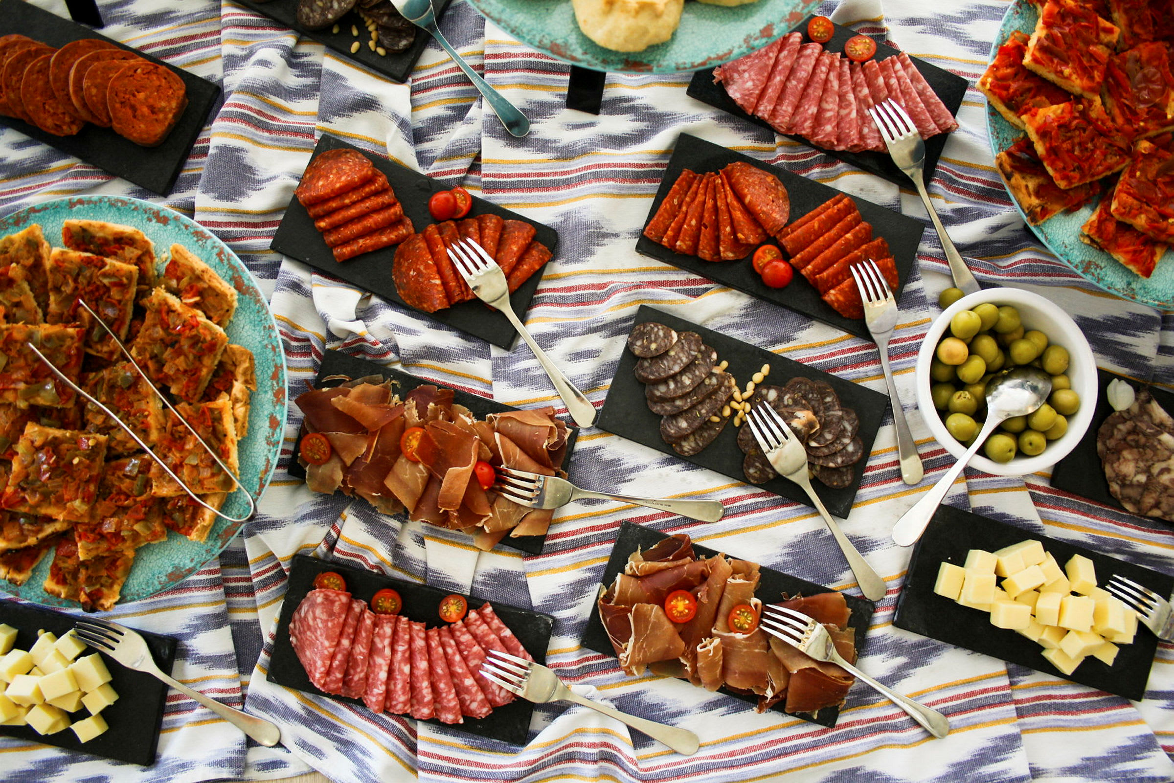 En matoppsett med forskjellige tapas inkludert kjøttprodukter, ost og oliven. (AI-generert tekst)