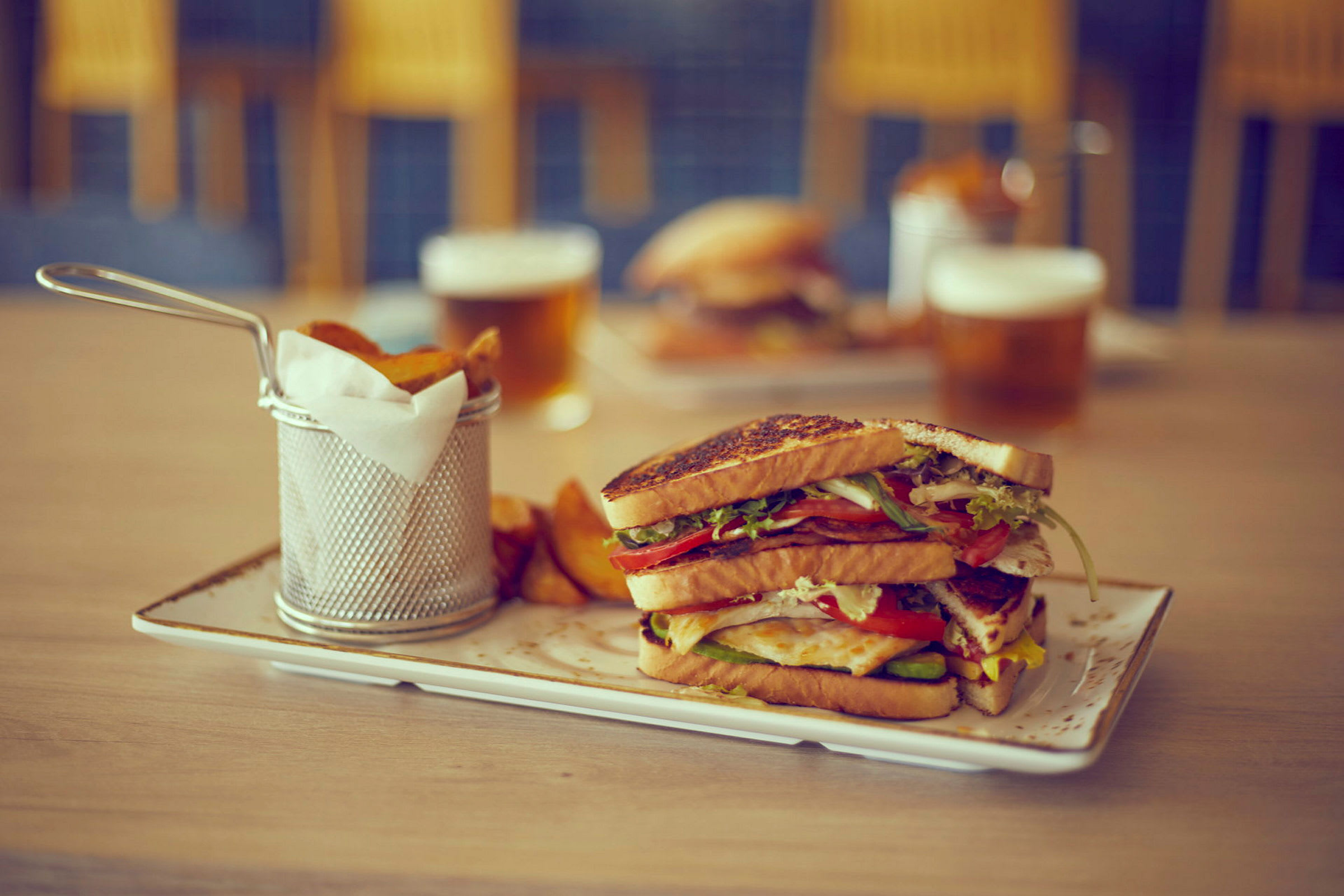 En tallerken med sandwich og pommes frites ved siden av en drikke. (AI-generert tekst)
