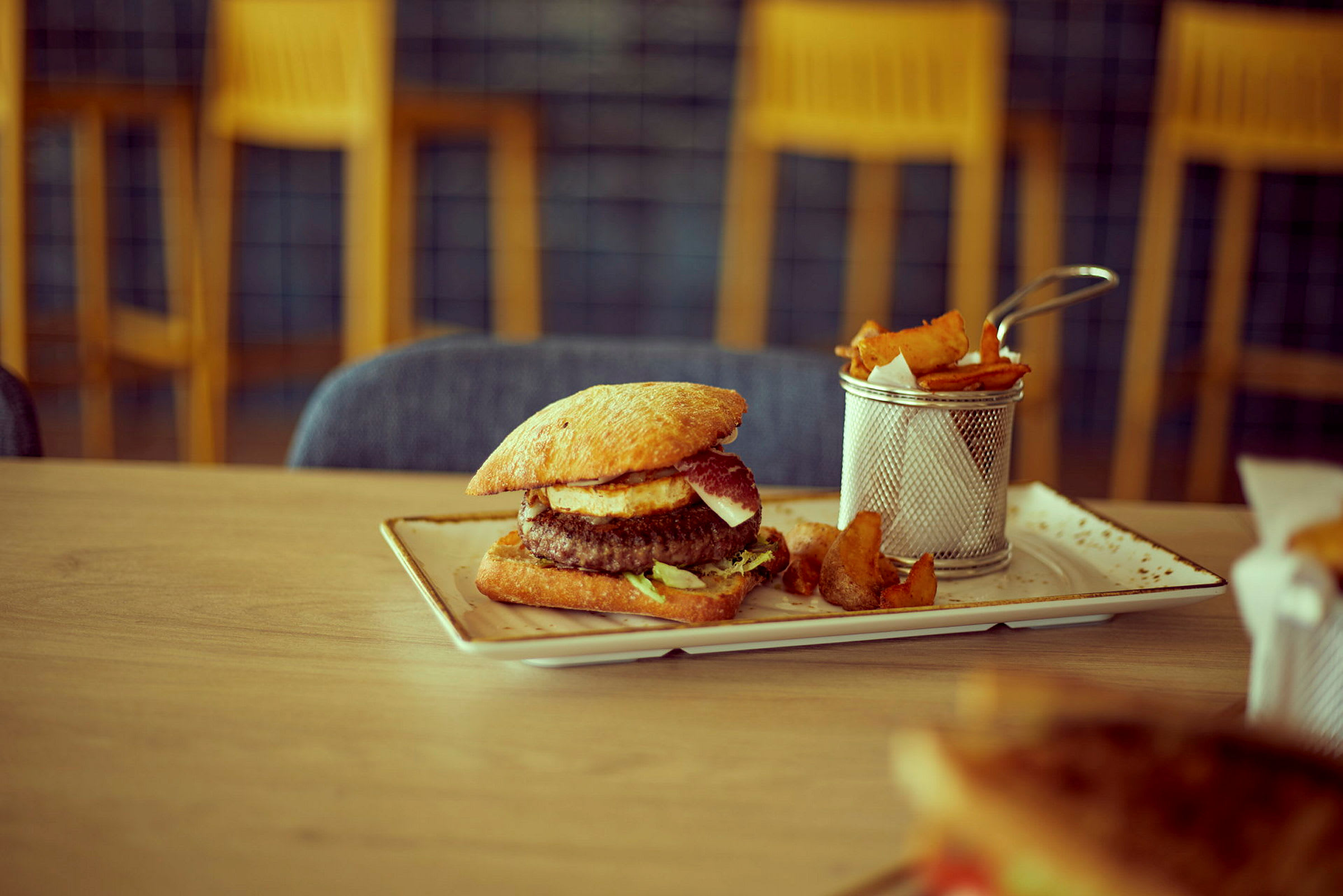 En tallerken med hamburger og tilhørende pommes frites. (AI-generert tekst)