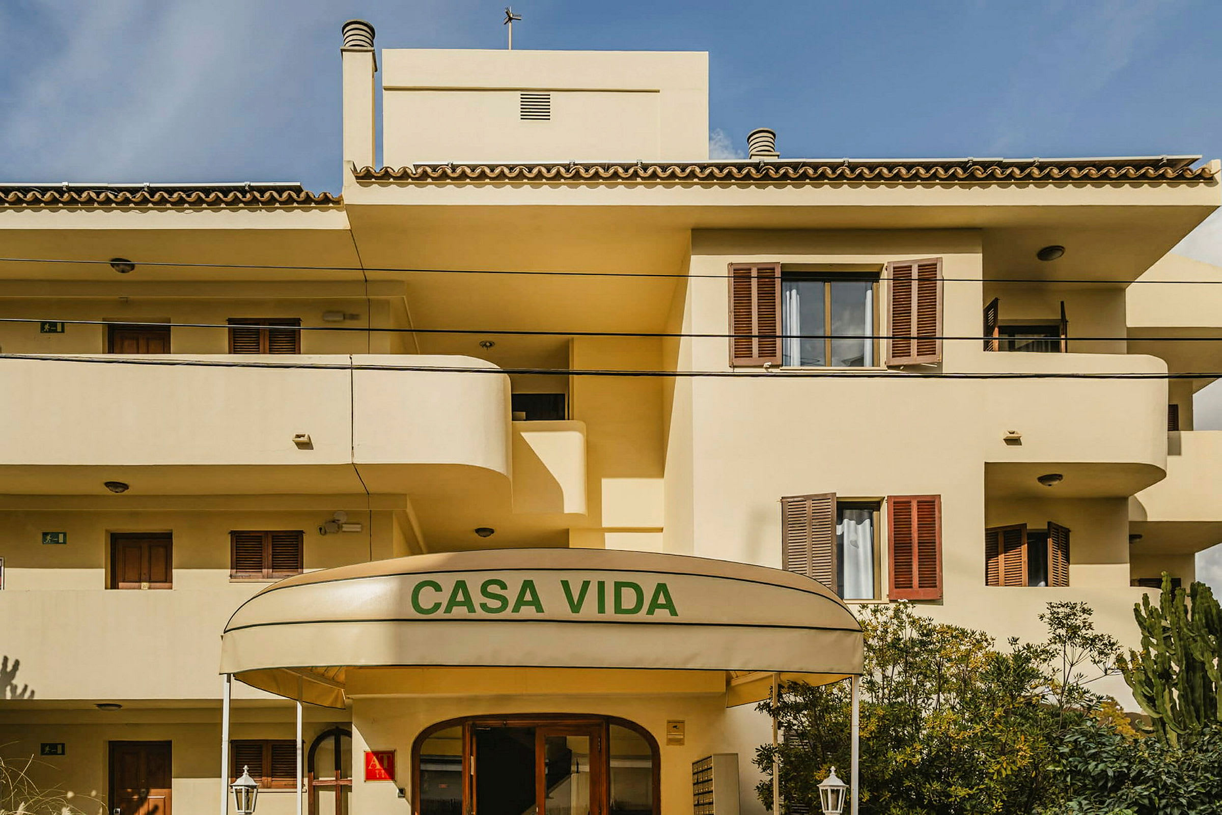 En gulmalet bygning med balkonger og en overbygning over inngangen som har teksten 'Casa Vida'. (AI-generert tekst)