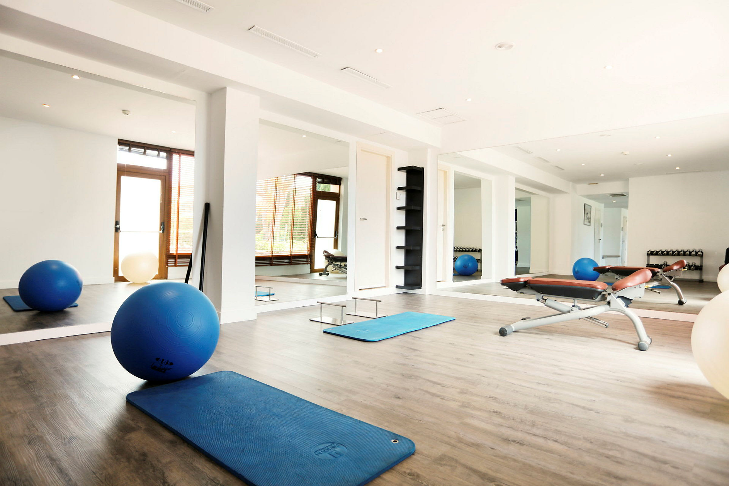 Et lyst treningsstudio med treningsmatter, pilatesballer og benker. (AI-generert tekst)