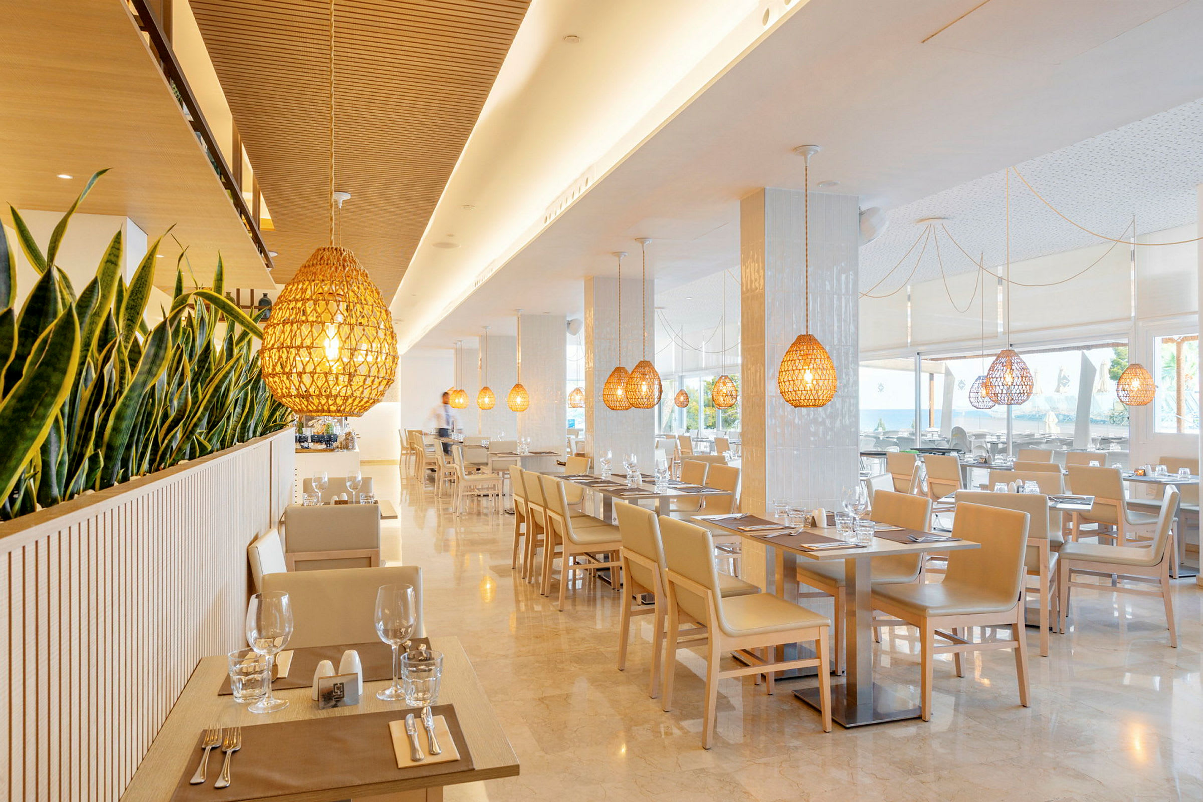 En moderne og lys restaurant med planter som skillevegger og hengende lamper i tredesign. (AI-generert tekst)